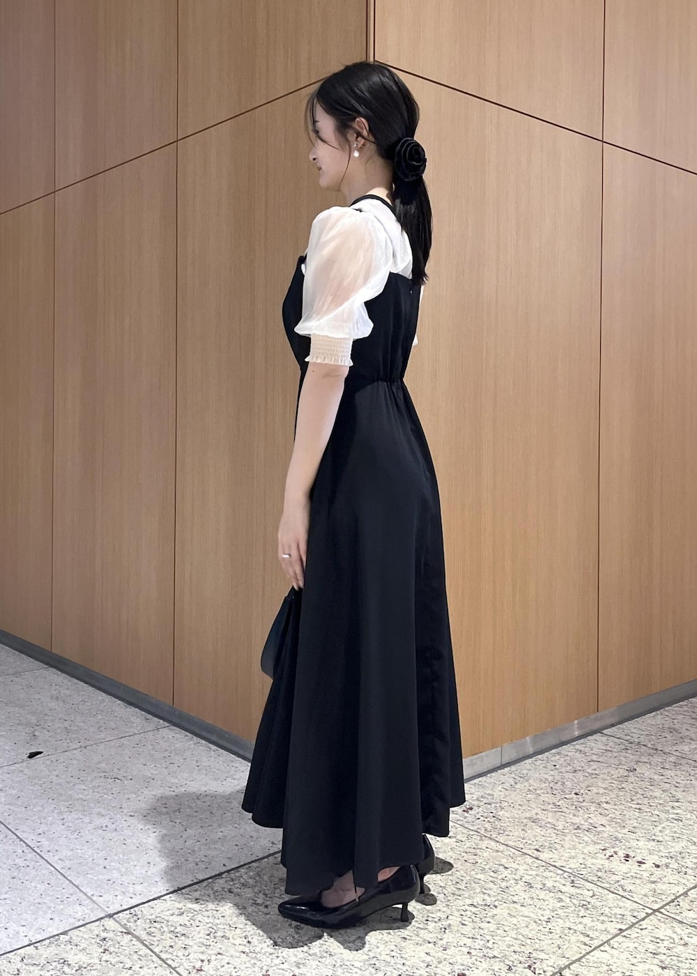 ブラック系のハンドバッグ、ブラック系のパンプス、ブラック系のワンピースを着用したレディースの春コーディネートの2枚目の写真