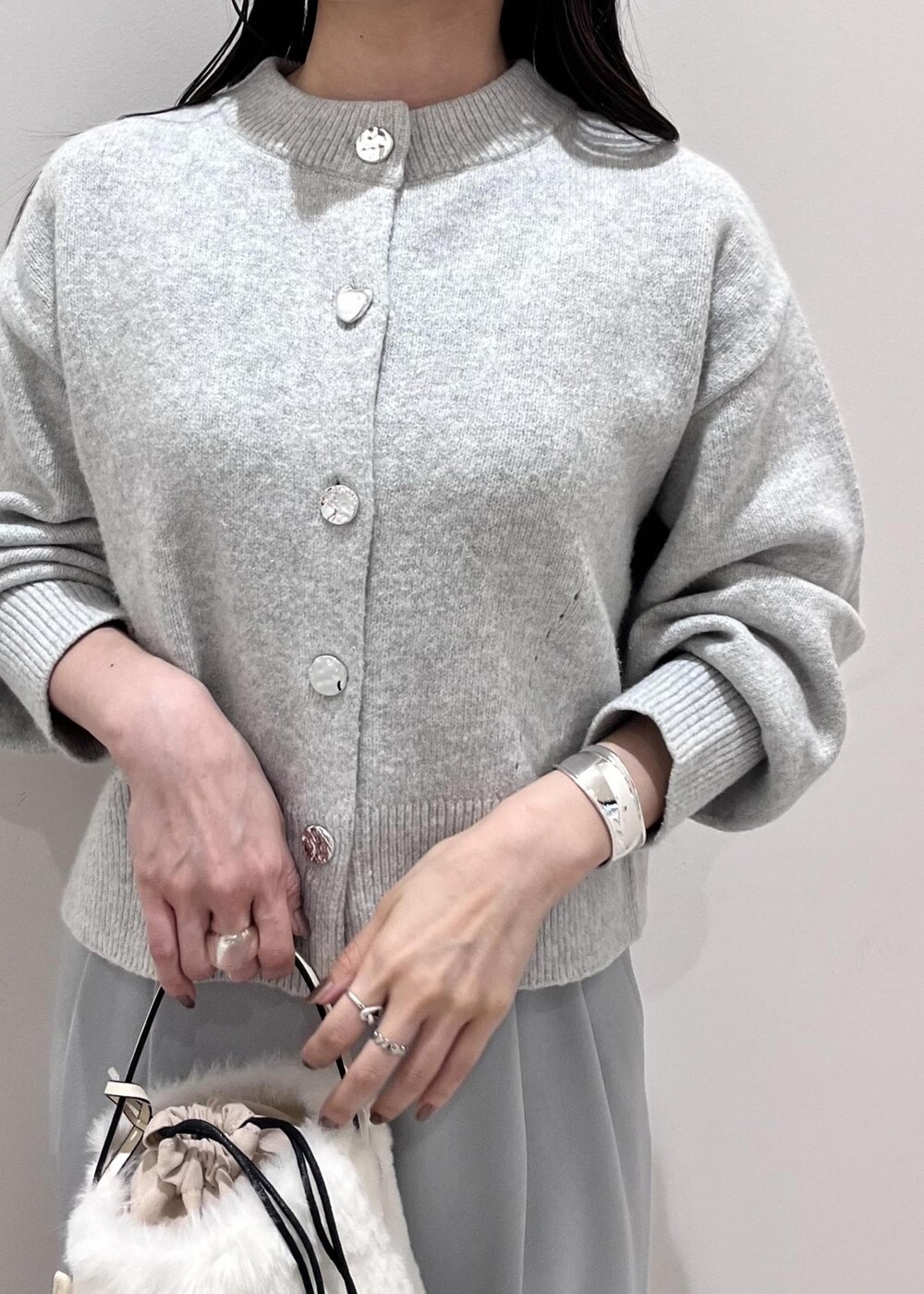 シルバー系のパンプス、ホワイト系のショルダーバッグ、グレー系のカーディガン/ボレロを着用したレディースの秋コーディネートの5枚目の写真