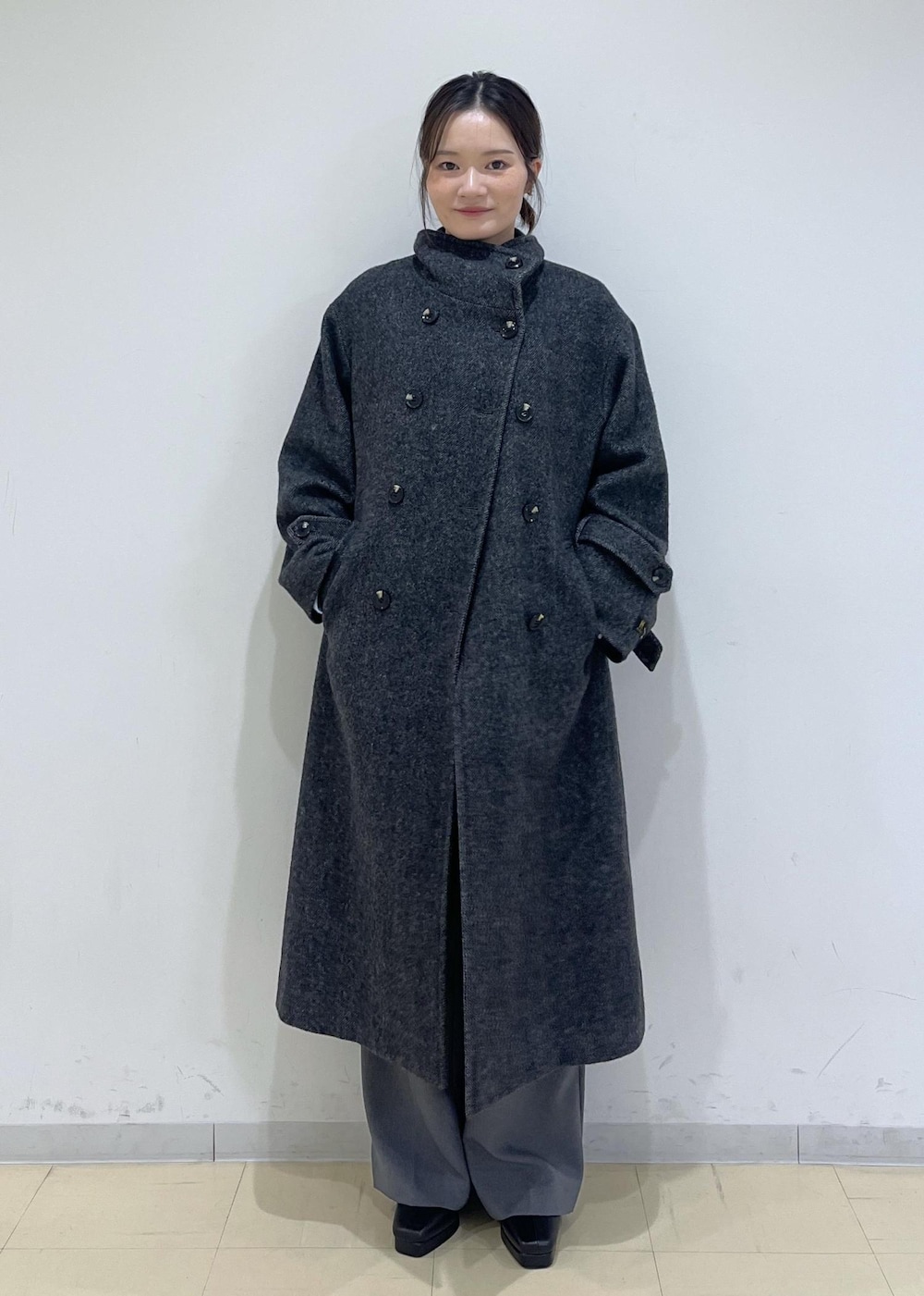 グレー系のスラックス、ホワイト系のベスト、ブルー系のニット/セーターを着用したレディースの秋コーディネートの4枚目の写真