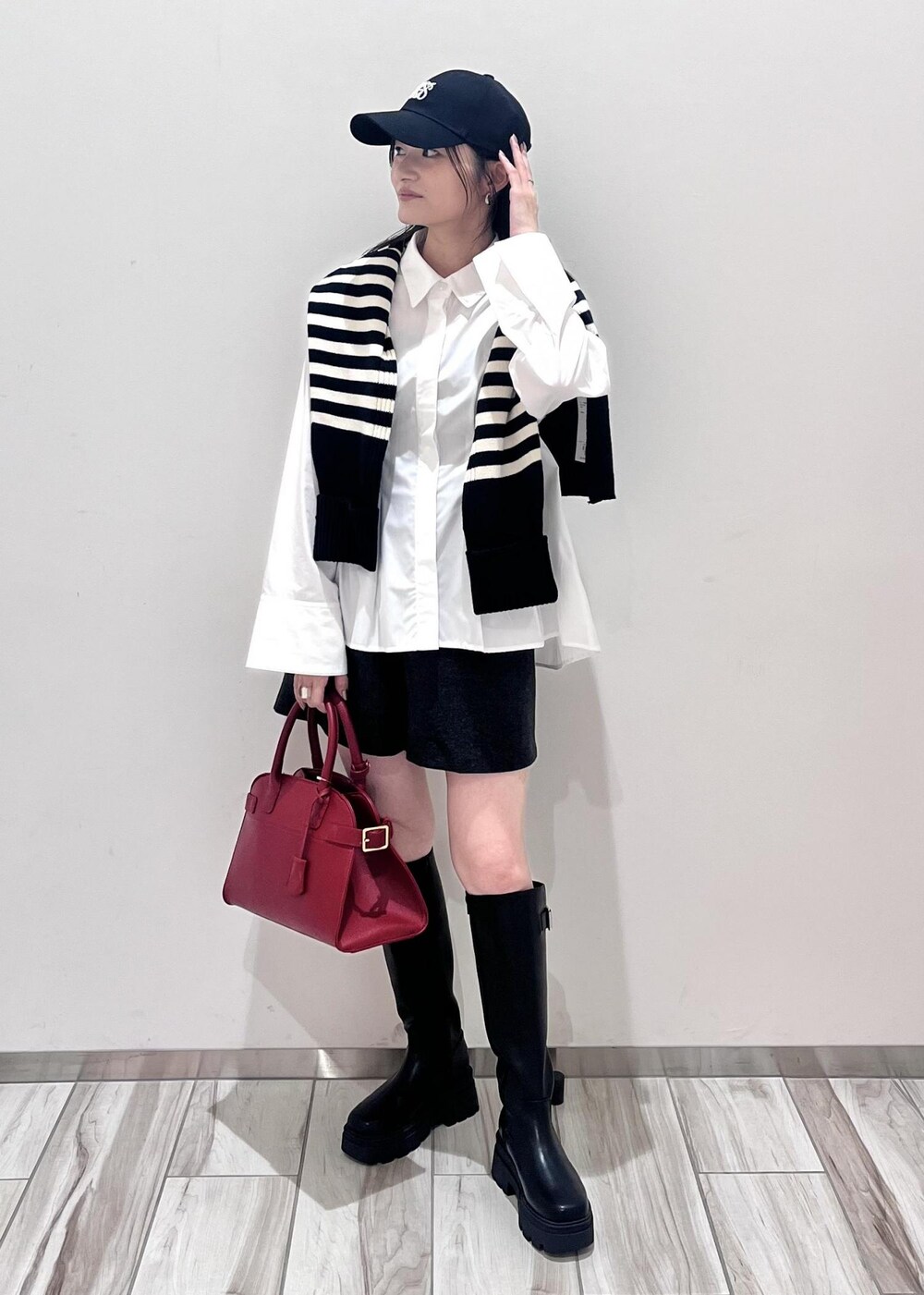 レッド系のトートバッグ、グレー系のその他パンツ、ブラック系のブーツを着用したレディースの秋コーディネートの2枚目の写真