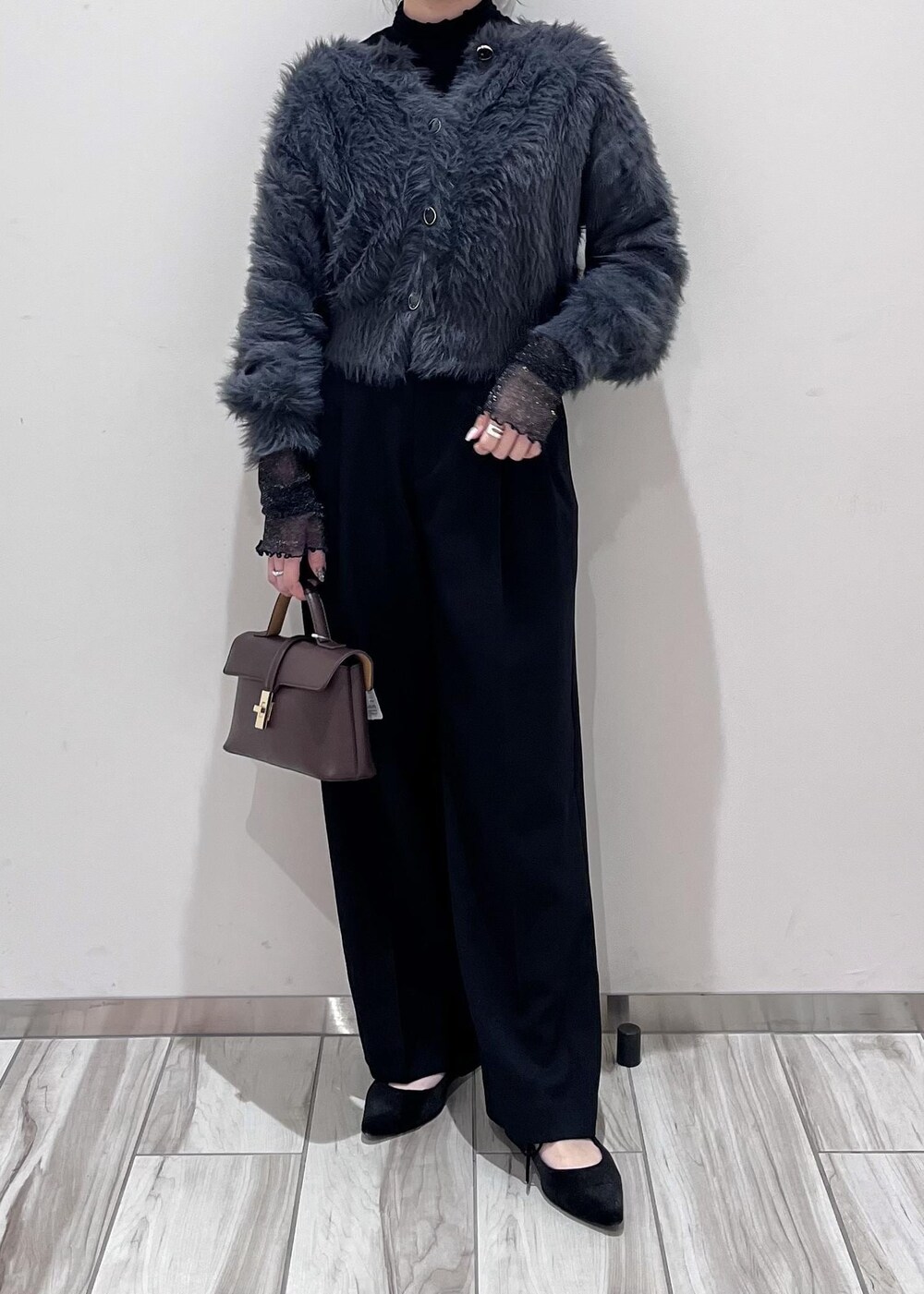 ブラウン系のショルダーバッグ、ブラック系のスラックス、グレー系のカーディガン/ボレロを着用したレディースの冬コーディネートの10枚目の写真