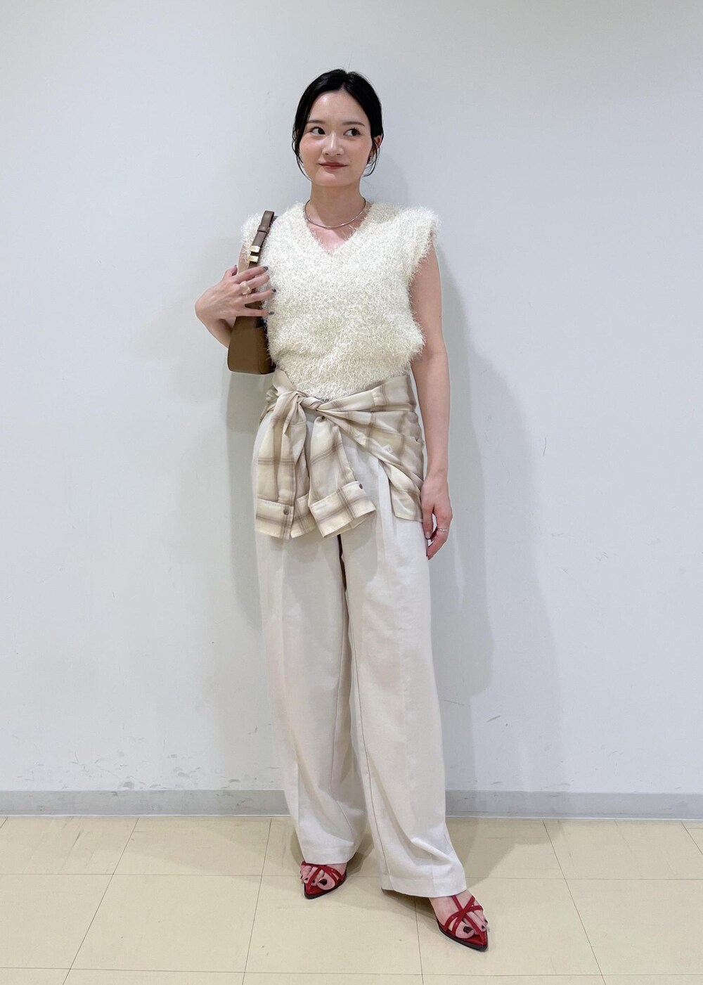 レッド系のサンダル、ベージュ系のシャツ/ブラウス、ホワイト系のスラックスを着用したレディースの夏コーディネートの2枚目の写真