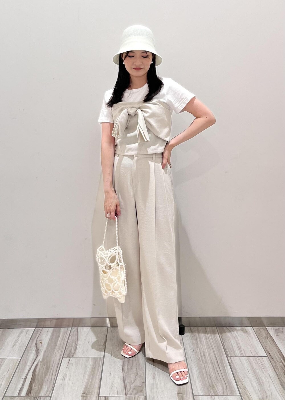 ホワイト系のサンダル、ホワイト系のスラックス、ホワイト系のハンドバッグを着用したレディースの夏コーディネートの6枚目の写真