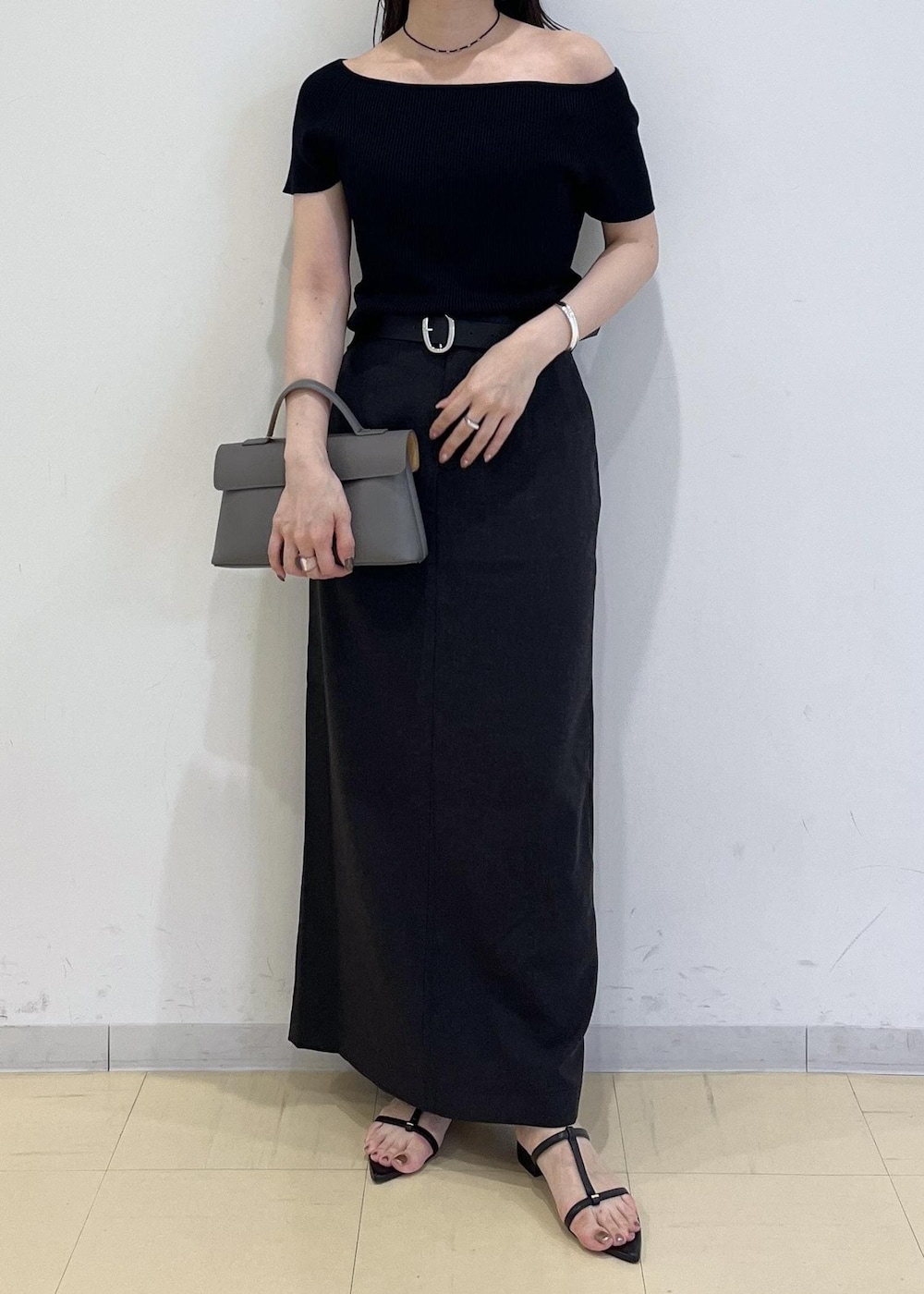 グレー系のショルダーバッグ、グレー系のスカート、ブラック系のニット/セーターを着用したレディースの夏コーディネートの9枚目の写真