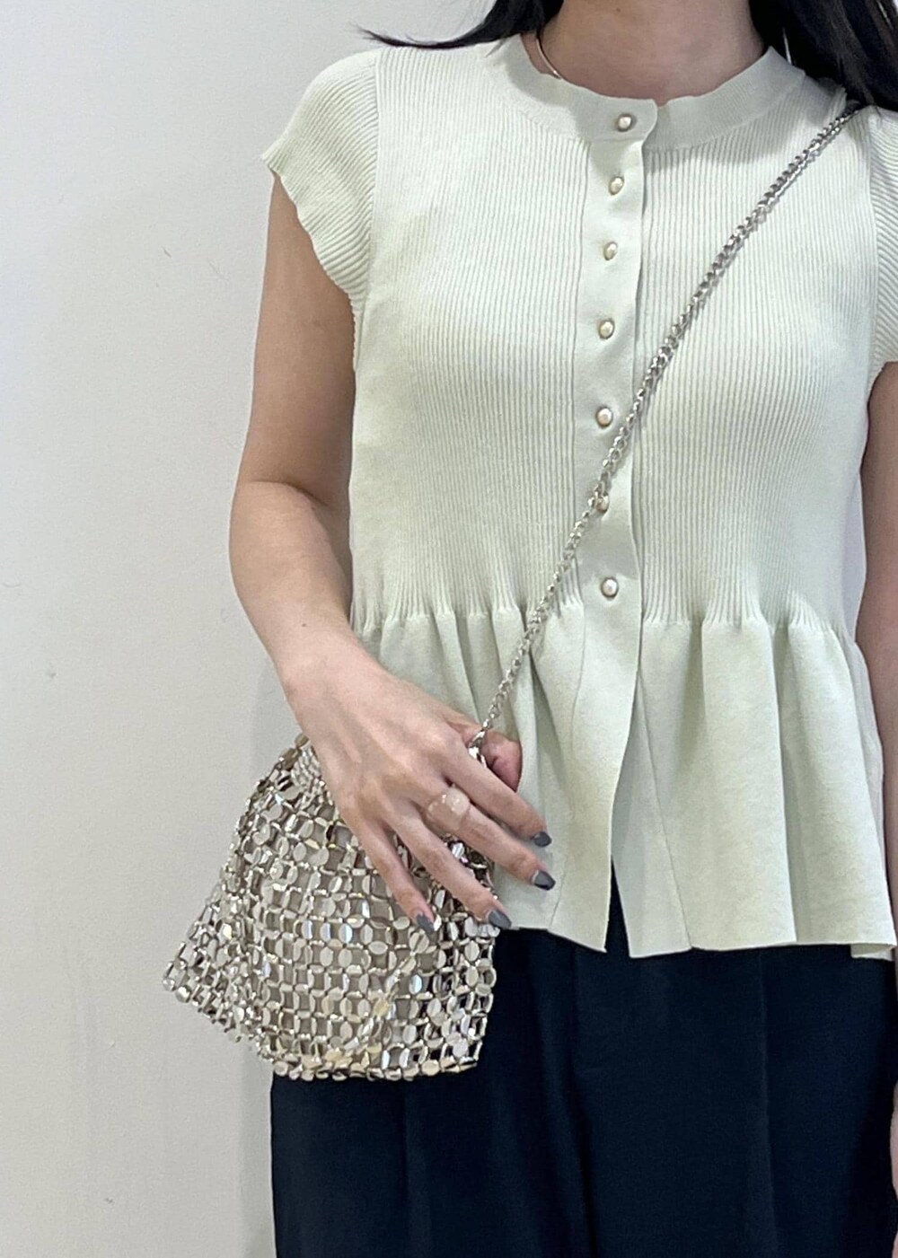 シルバー系のパンプス、シルバー系のハンドバッグ、ブルー系のスラックスを着用したレディースの夏コーディネートの4枚目の写真