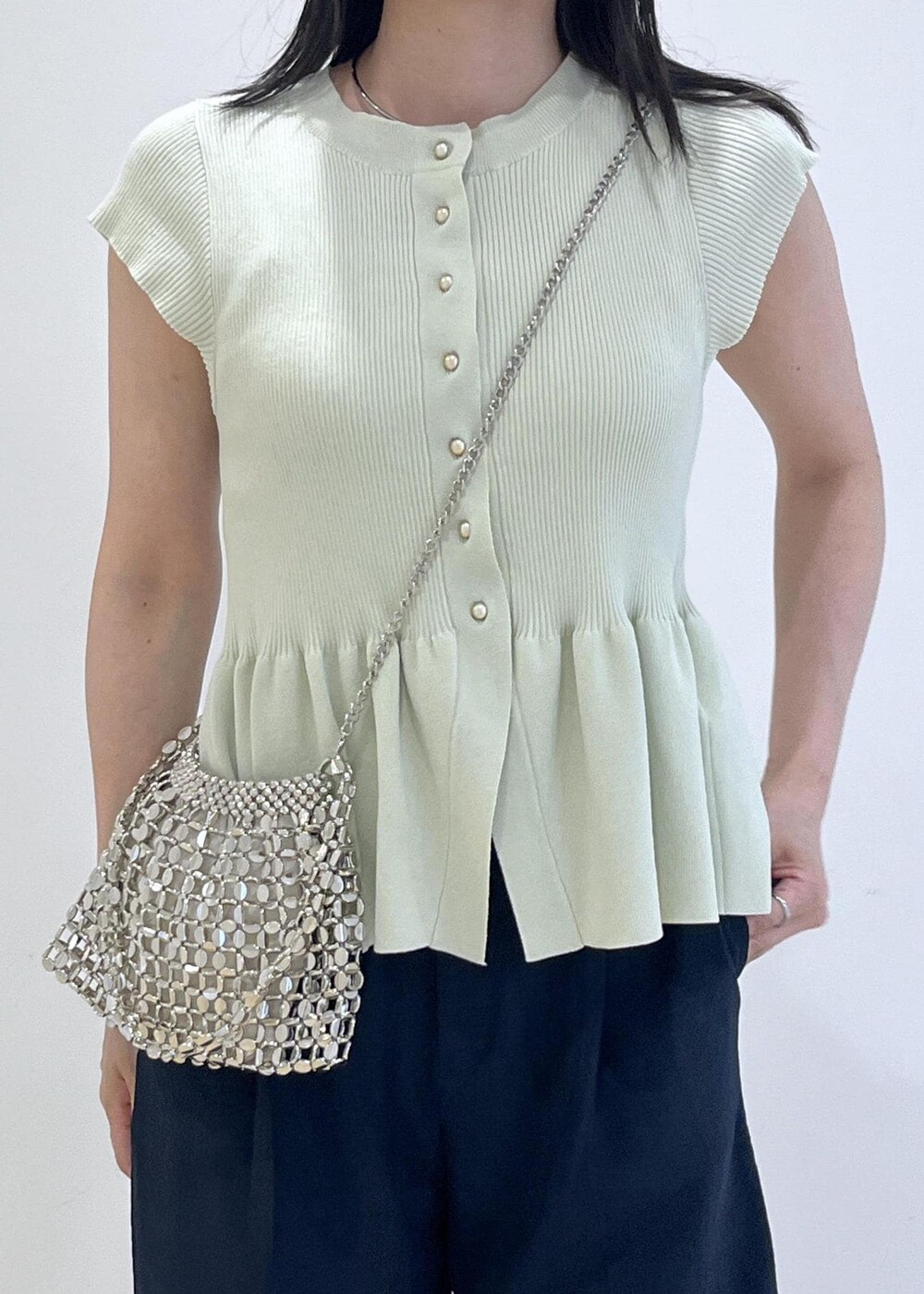 シルバー系のパンプス、シルバー系のハンドバッグ、ブルー系のスラックスを着用したレディースの夏コーディネートの10枚目の写真