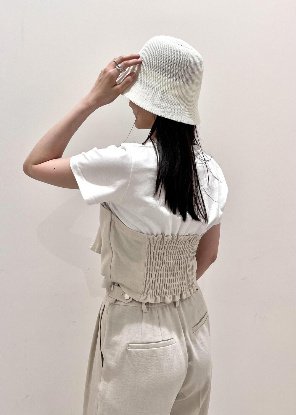 ホワイト系のサンダル、ホワイト系のスラックス、ホワイト系のハンドバッグを着用したレディースの夏コーディネートの3枚目の写真