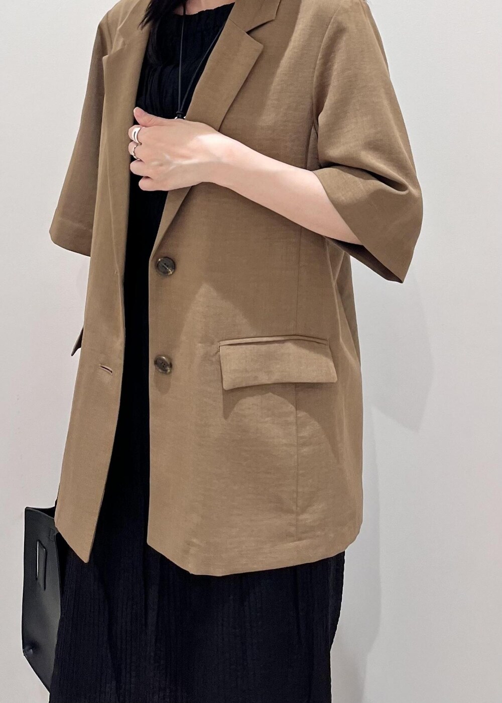 ブラック系のサンダル、ブラック系のハンドバッグ、ブラウン系のテーラードジャケットを着用したレディースの夏コーディネートの3枚目の写真