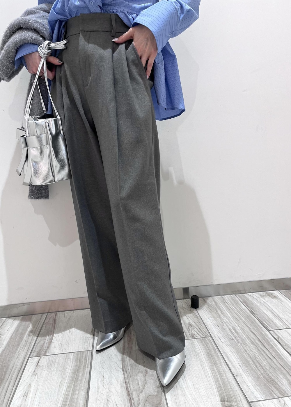 シルバー系のショルダーバッグ、シルバー系のブーツ、グレー系のスラックスを着用したレディースの冬コーディネートの7枚目の写真