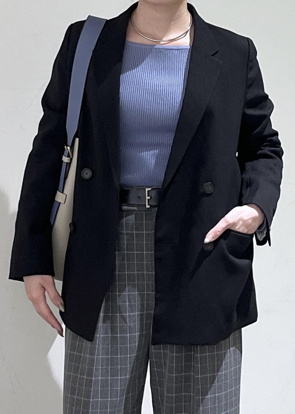 ベージュ系のトートバッグ、ブラック系のテーラードジャケット、ブラック系のチェスターコートを着用したレディースの冬コーディネートの3枚目の写真