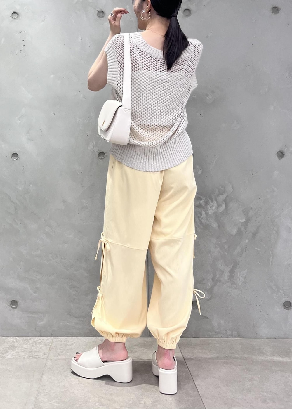 ホワイト系のショルダーバッグ、ホワイト系のサンダル、ホワイト系のベストを着用したレディースの夏コーディネートの3枚目の写真