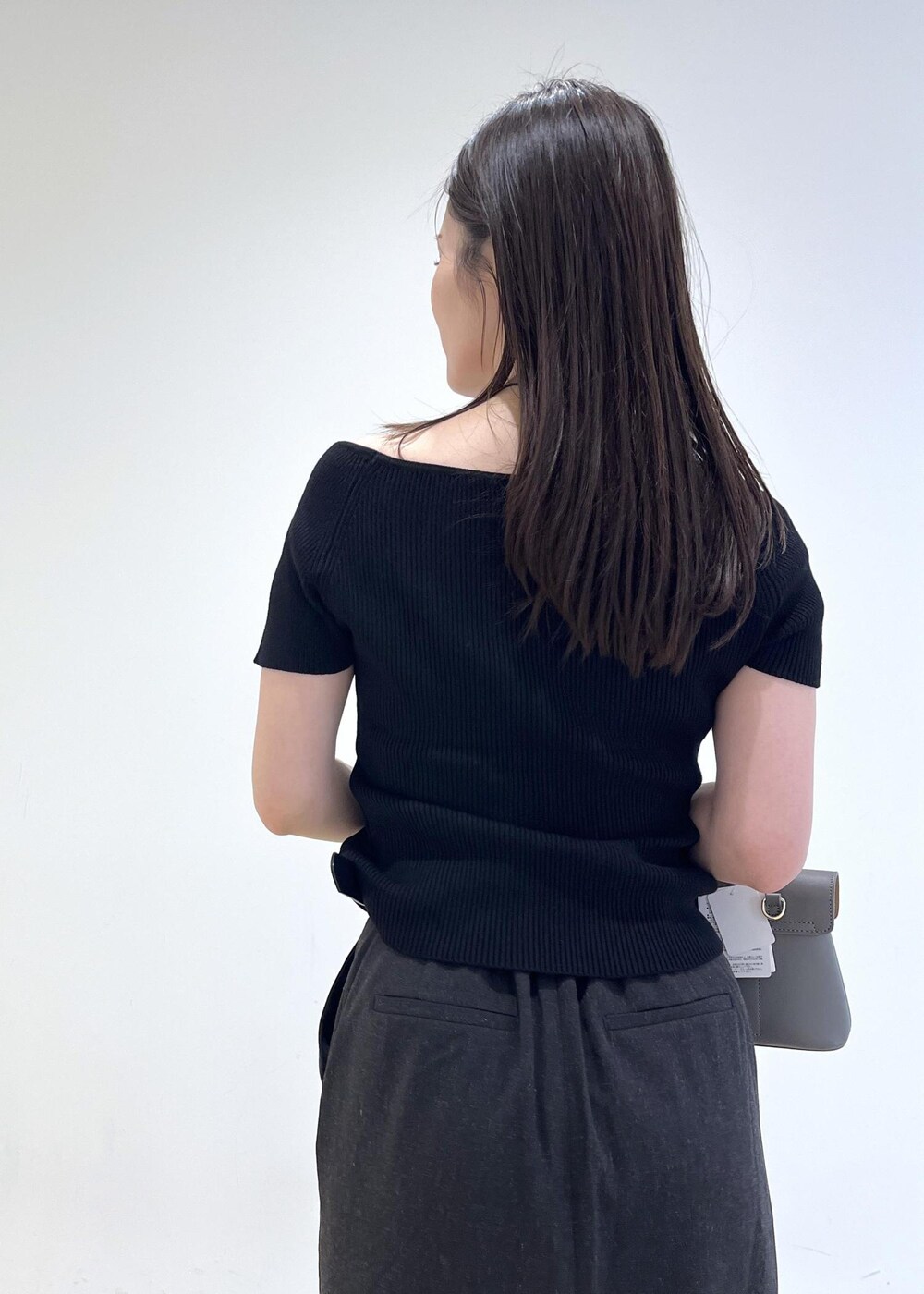 グレー系のショルダーバッグ、グレー系のスカート、ブラック系のニット/セーターを着用したレディースの夏コーディネートの10枚目の写真