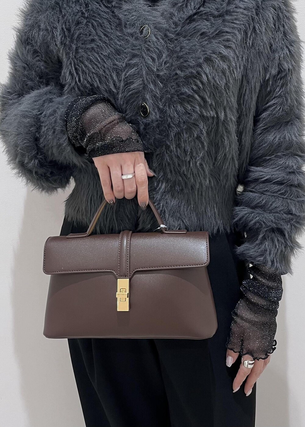 ブラウン系のショルダーバッグ、ブラック系のスラックス、グレー系のカーディガン/ボレロを着用したレディースの冬コーディネートの9枚目の写真