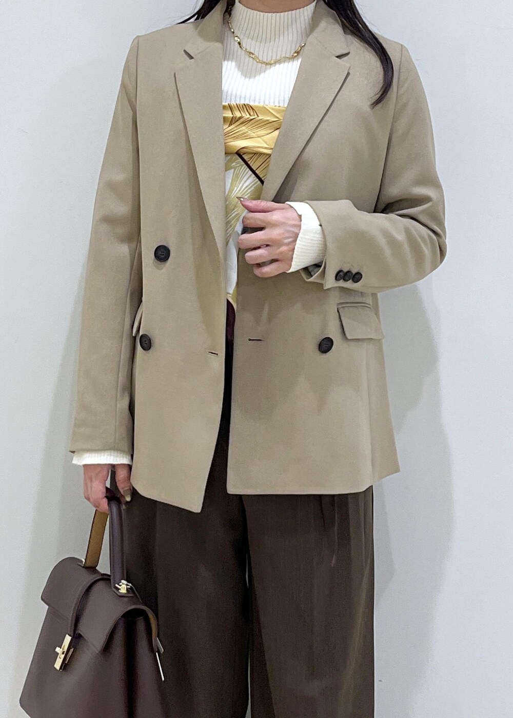 ブラウン系のハンドバッグ、ホワイト系のパンプス、ホワイト系のニット/セーターを着用したレディースの秋コーディネートの8枚目の写真