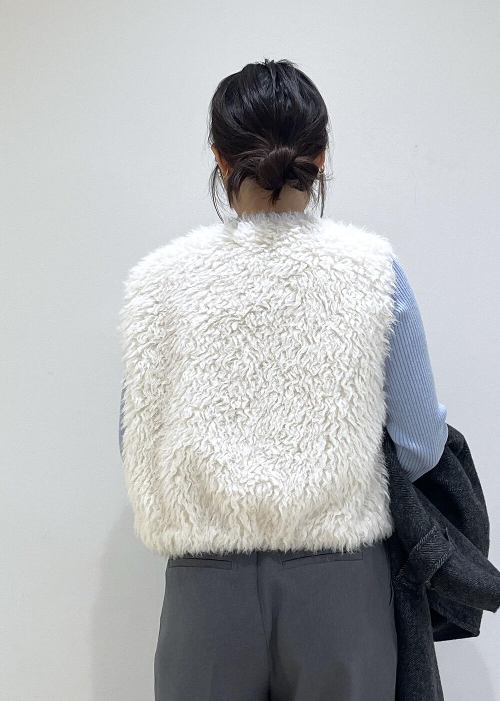 グレー系のスラックス、ホワイト系のベスト、ブルー系のニット/セーターを着用したレディースの秋コーディネートの10枚目の写真