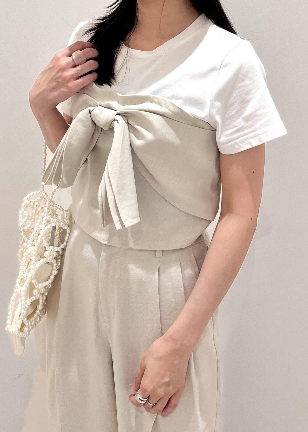 ホワイト系のサンダル、ホワイト系のスラックス、ホワイト系のハンドバッグを着用したレディースの夏コーディネートの2枚目の写真