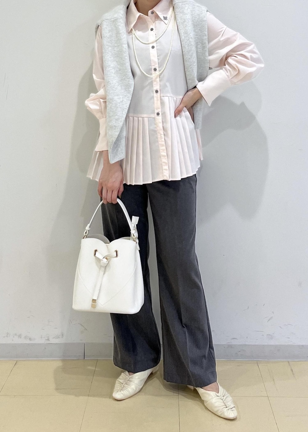 ホワイト系のショルダーバッグ、ホワイト系のパンプス、グレー系のスラックスを着用したレディースの秋コーディネートの4枚目の写真