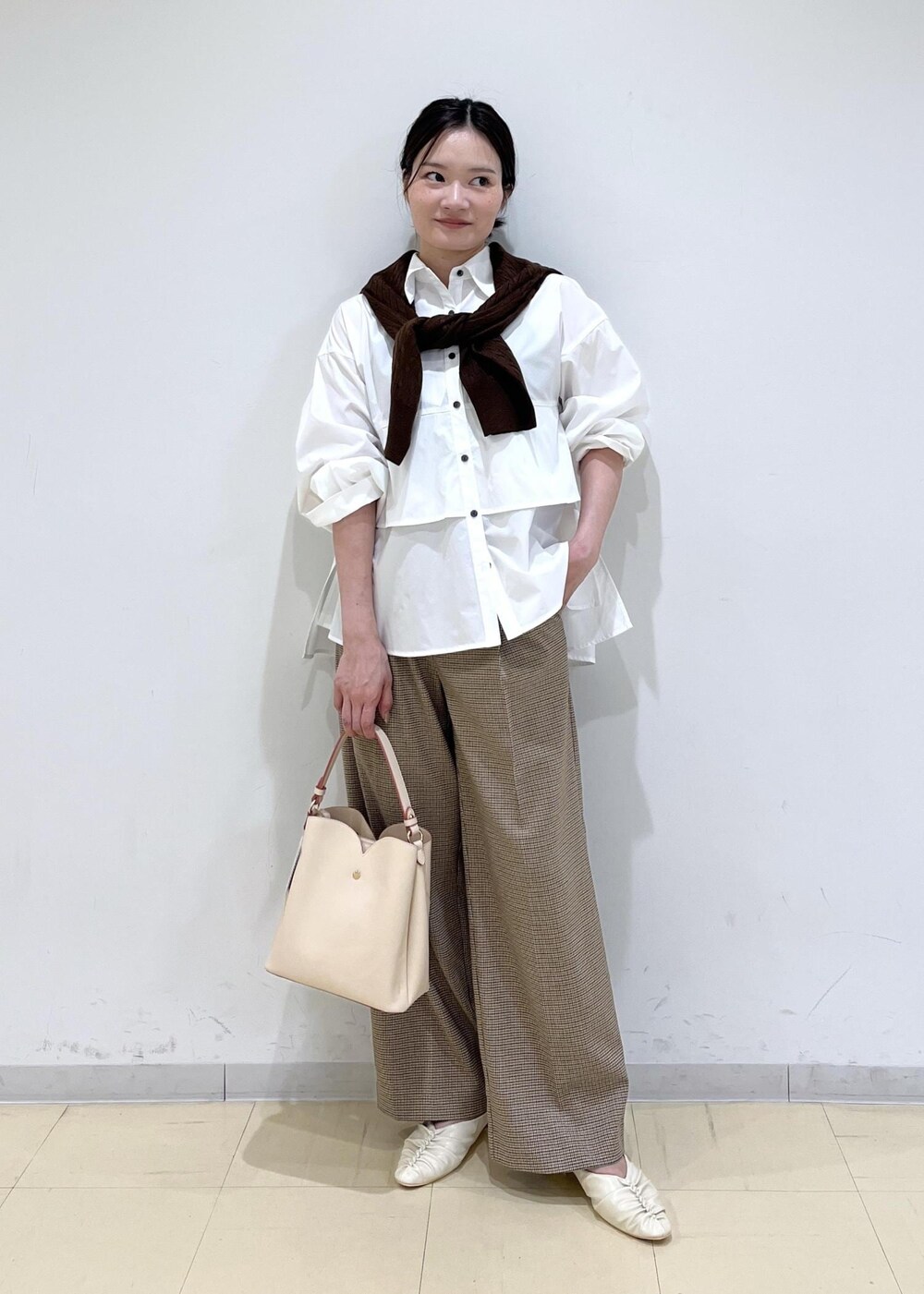 ベージュ系のショルダーバッグ、ベージュ系のスラックス、ホワイト系のシャツ/ブラウスを着用したレディースの秋コーディネートの2枚目の写真
