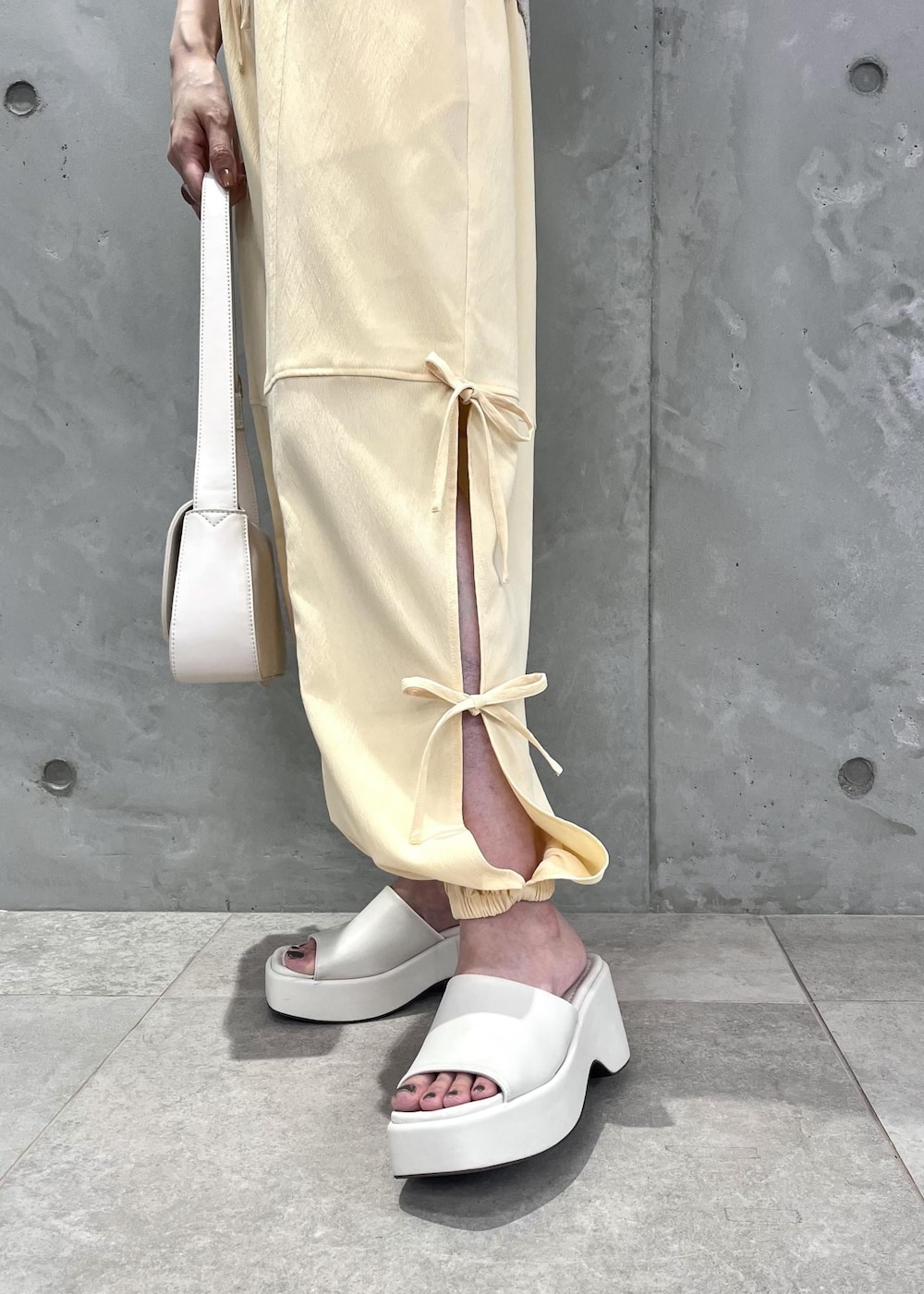 ホワイト系のショルダーバッグ、ホワイト系のサンダル、ホワイト系のベストを着用したレディースの夏コーディネートの4枚目の写真