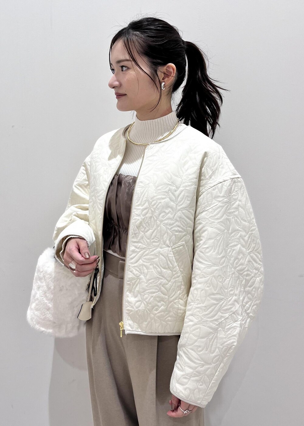 ホワイト系のショルダーバッグ、ホワイト系のブーツ、ホワイト系のブルゾンを着用したレディースの秋コーディネートの5枚目の写真