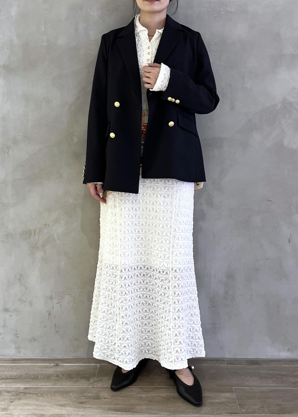 ブラック系のパンプス、ホワイト系のワンピース、ブルー系のテーラードジャケットを着用したレディースの春コーディネートの2枚目の写真