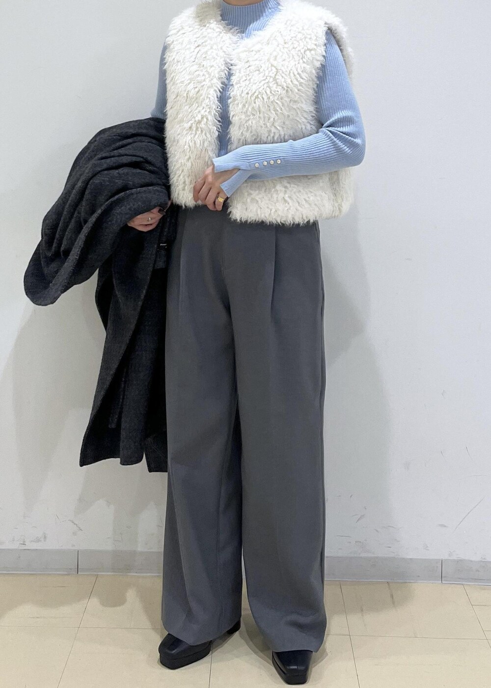 グレー系のスラックス、ホワイト系のベスト、ブルー系のニット/セーターを着用したレディースの秋コーディネートの8枚目の写真