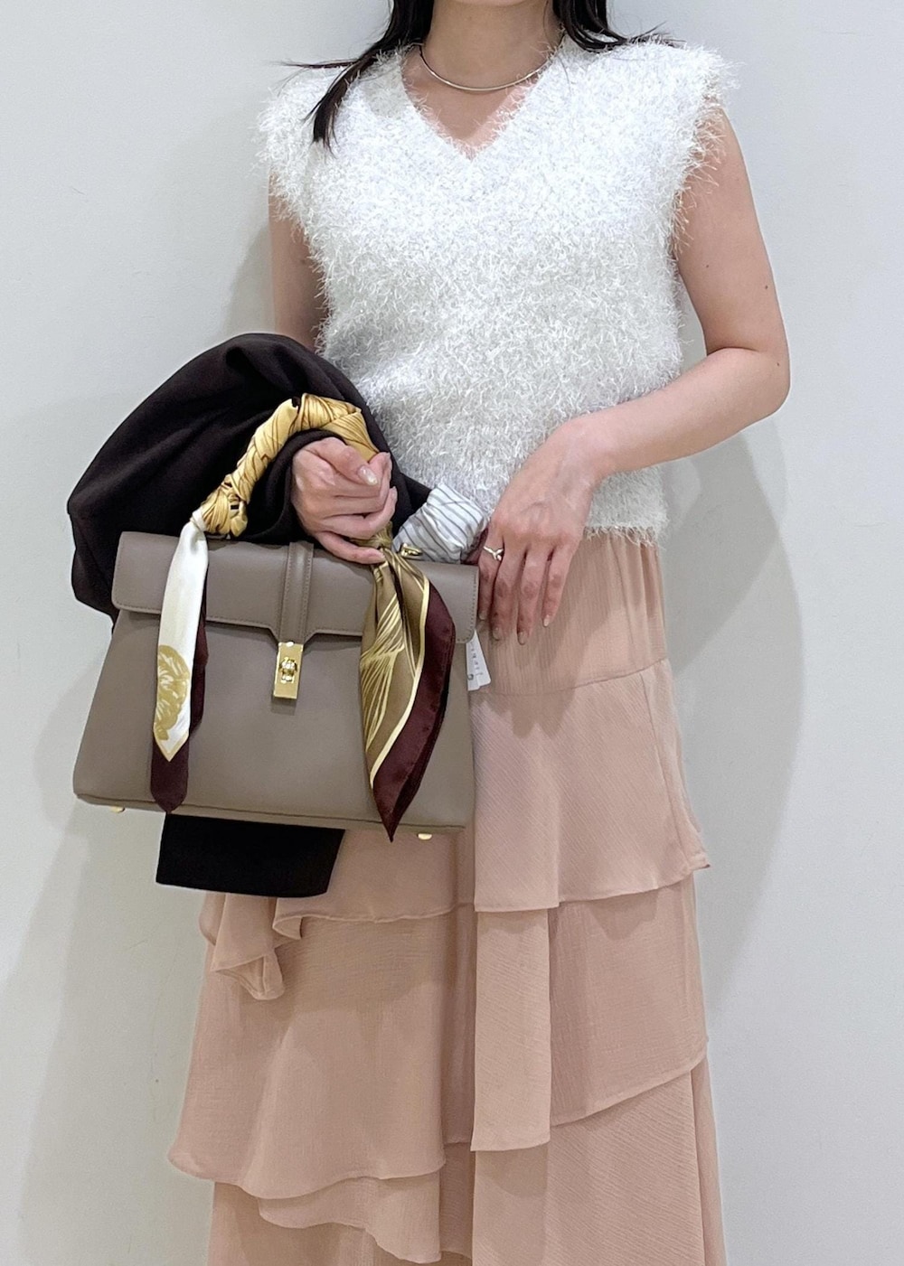 ベージュ系のハンドバッグ、ピンク系のスカート、ホワイト系のニット/セーターを着用したレディースの秋コーディネートの3枚目の写真