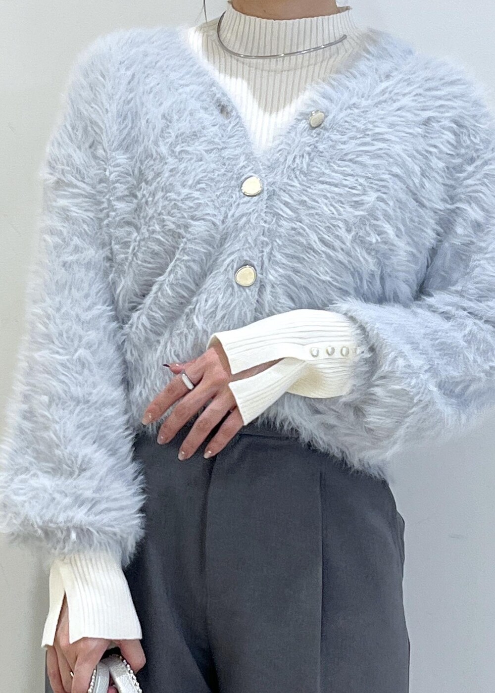 グレー系のスラックス、ホワイト系のパンプス、ブルー系のカーディガン/ボレロを着用したレディースの秋コーディネートの4枚目の写真