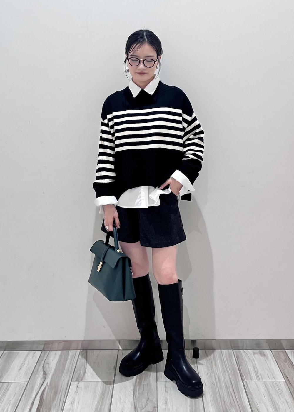 ブラック系のブーツ、ホワイト系のシャツ/ブラウス、ブラック系のニット/セーターを着用したレディースの秋コーディネートの3枚目の写真