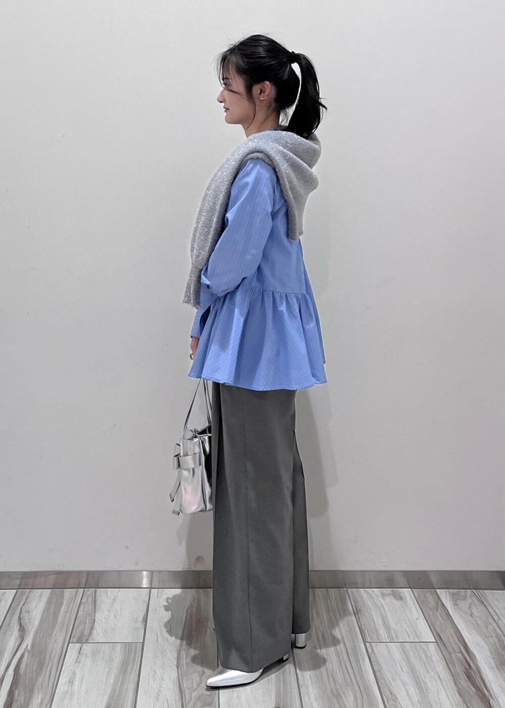 シルバー系のショルダーバッグ、シルバー系のブーツ、グレー系のスラックスを着用したレディースの冬コーディネートの2枚目の写真