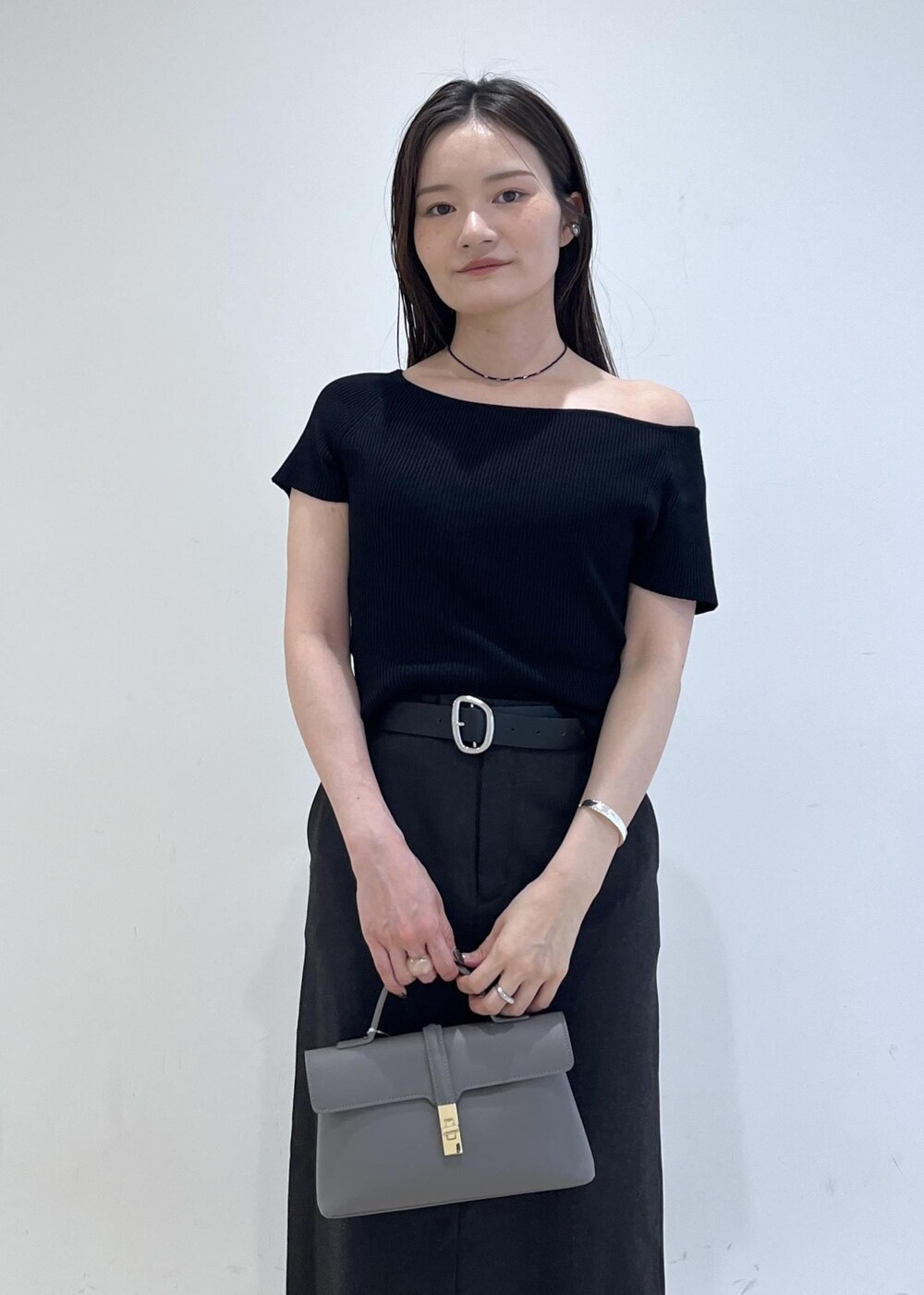 グレー系のショルダーバッグ、グレー系のスカート、ブラック系のニット/セーターを着用したレディースの夏コーディネートの5枚目の写真