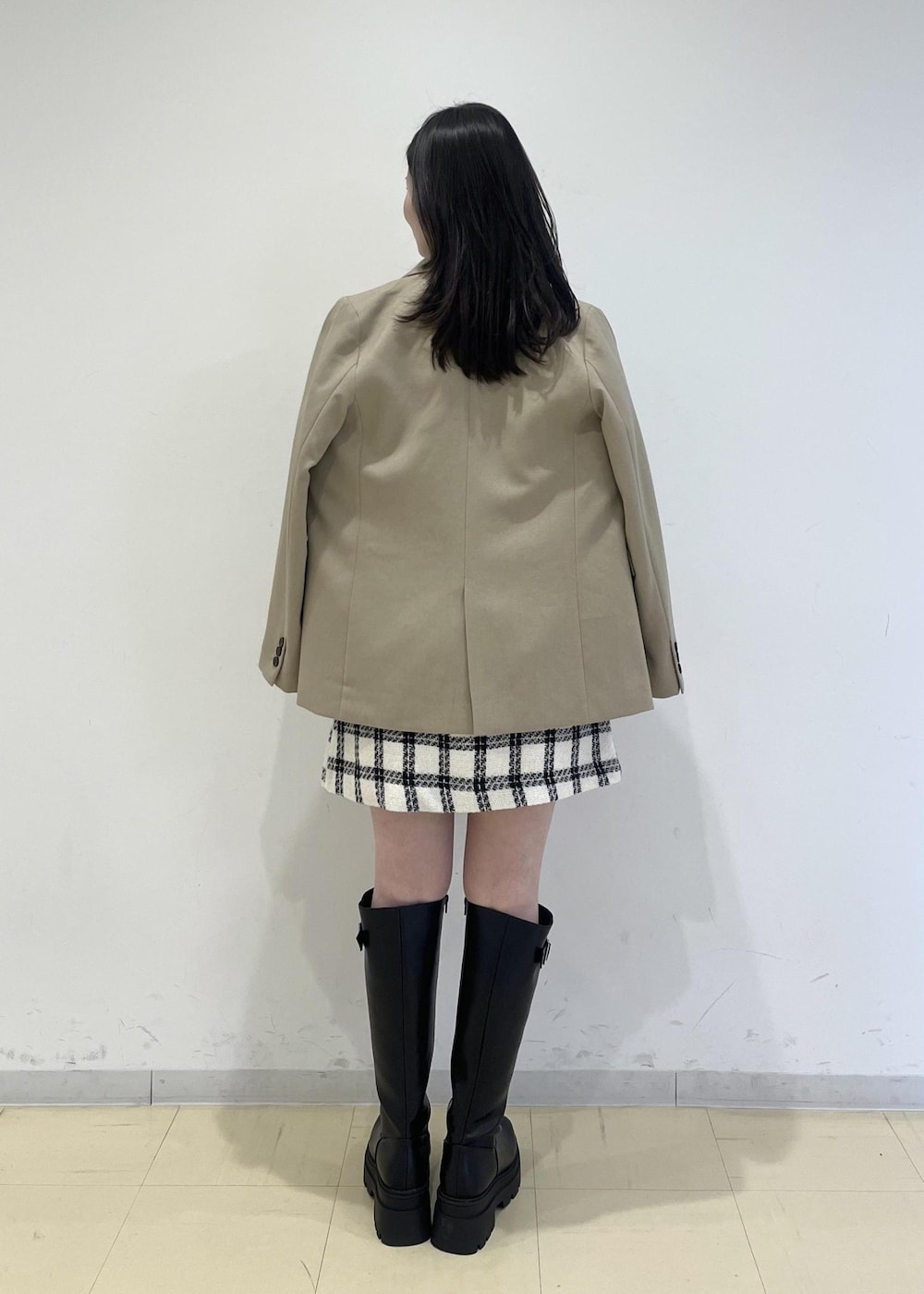 ブラック系のブーツ、ホワイト系のスカート、ホワイト系のニット/セーターを着用したレディースの冬コーディネートの2枚目の写真