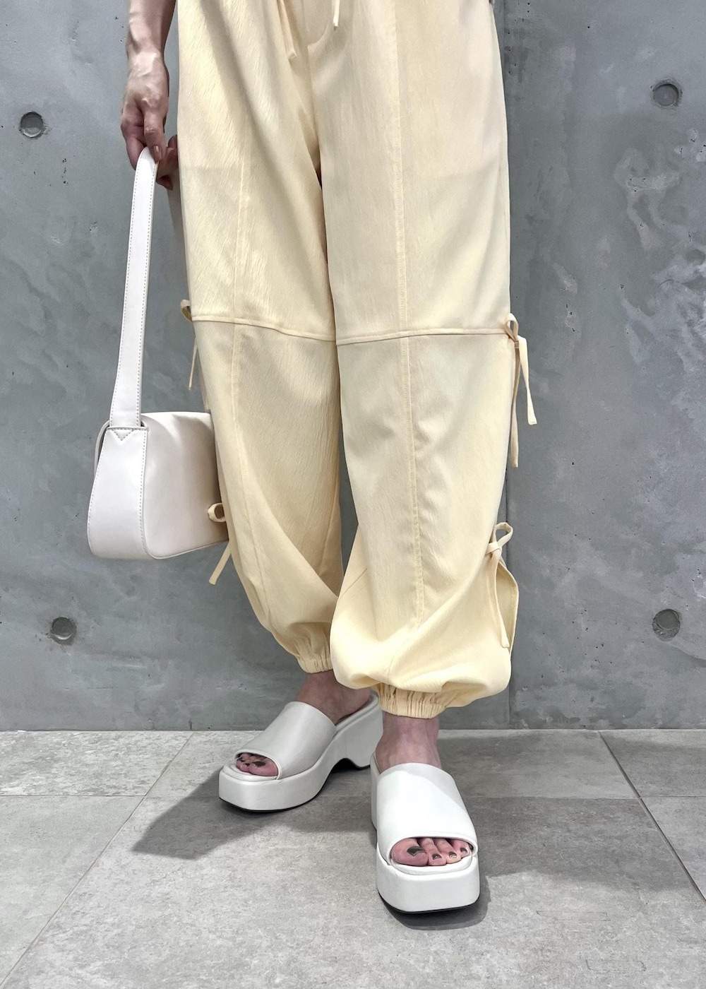 ホワイト系のショルダーバッグ、ホワイト系のサンダル、ホワイト系のベストを着用したレディースの夏コーディネートの5枚目の写真