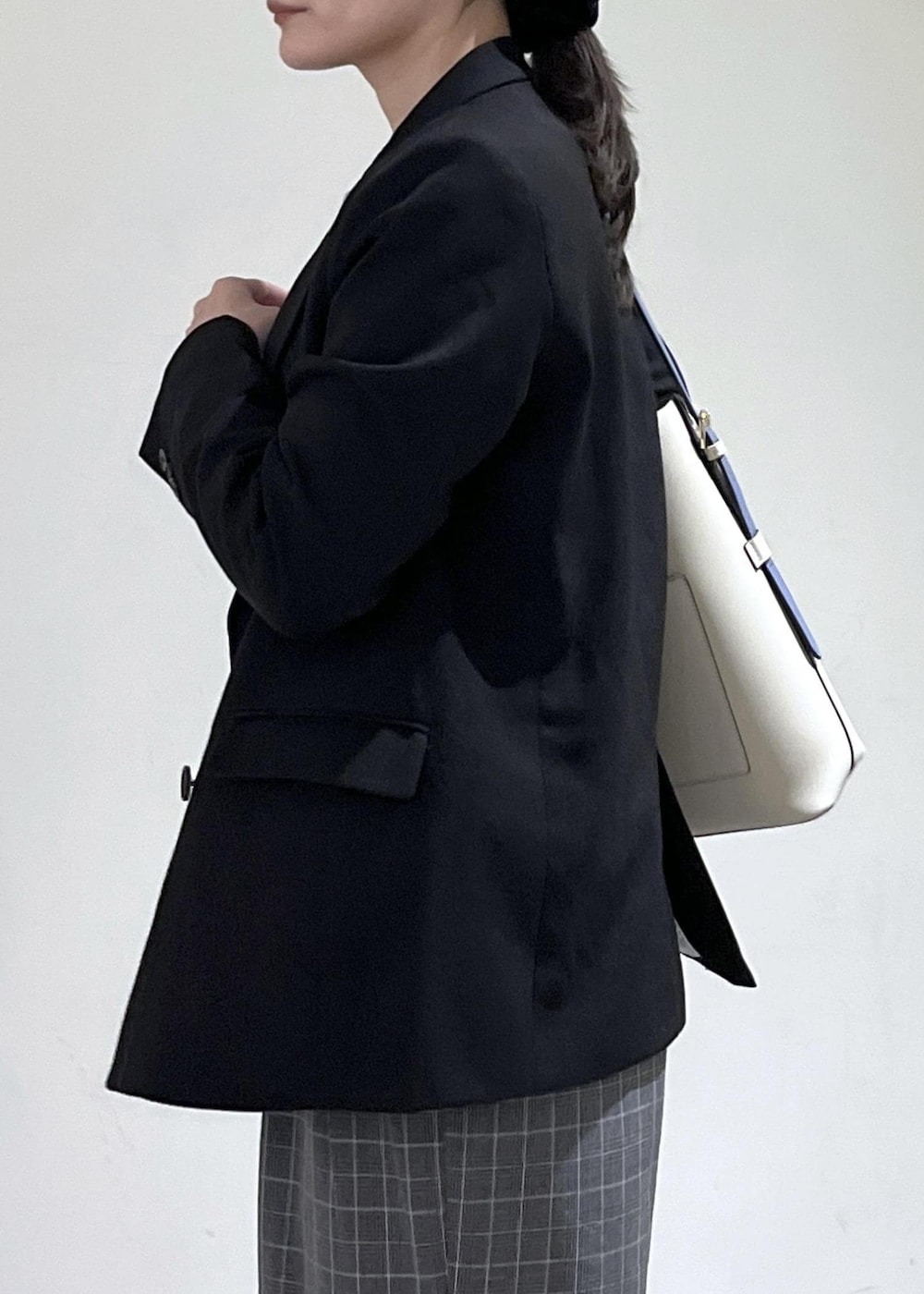 ベージュ系のトートバッグ、ブラック系のテーラードジャケット、ブラック系のチェスターコートを着用したレディースの冬コーディネートの4枚目の写真