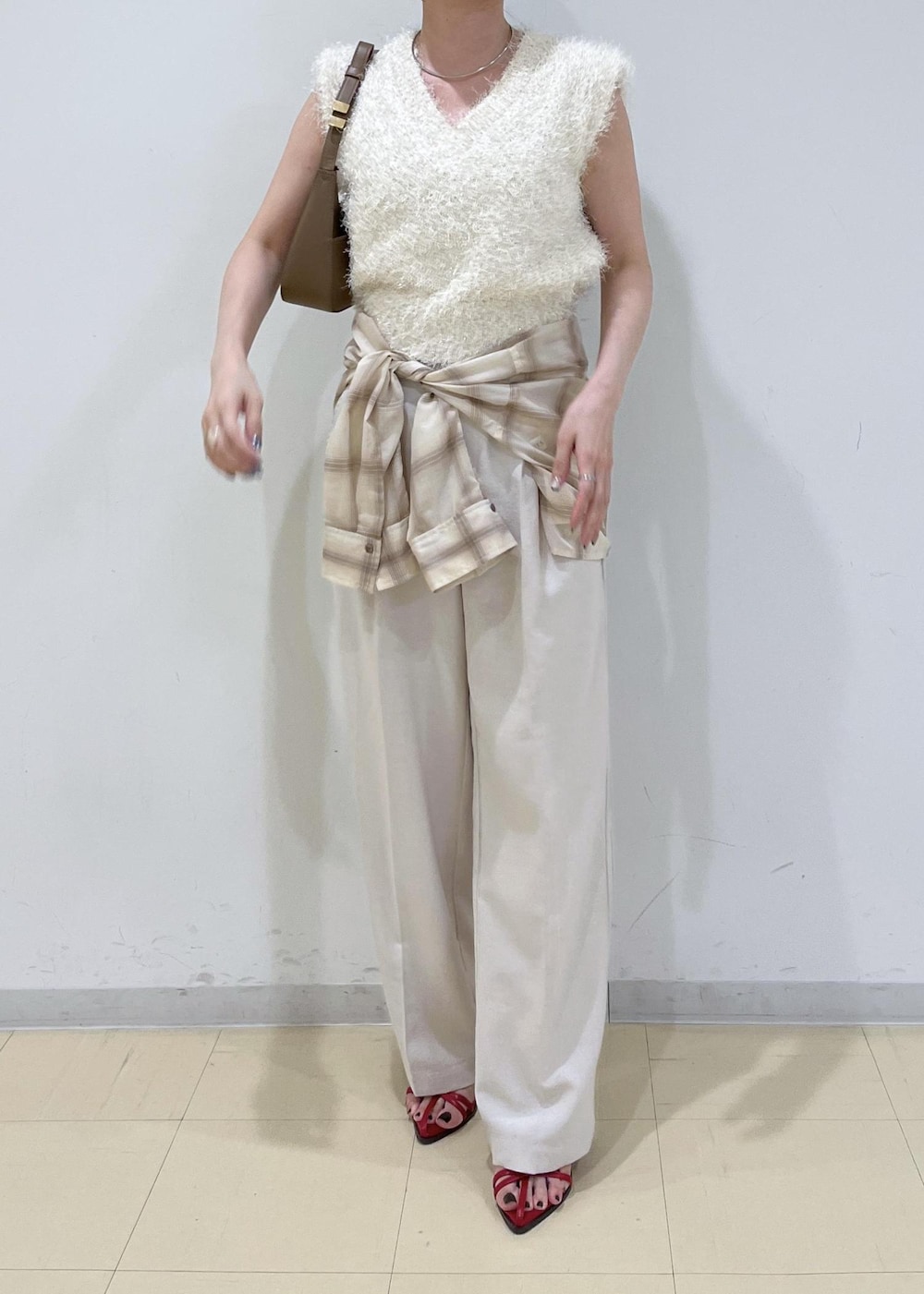 レッド系のサンダル、ベージュ系のシャツ/ブラウス、ホワイト系のスラックスを着用したレディースの夏コーディネートの3枚目の写真