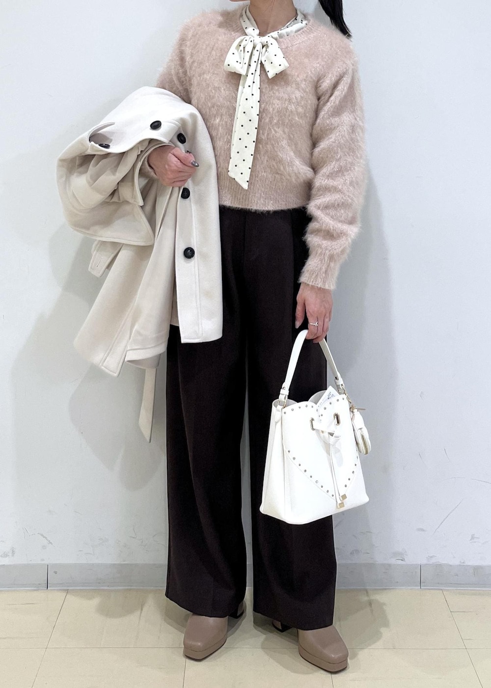 ブラウン系のスラックス、ベージュ系のチェスターコート、ベージュ系のブーツを着用したレディースの冬コーディネートの2枚目の写真