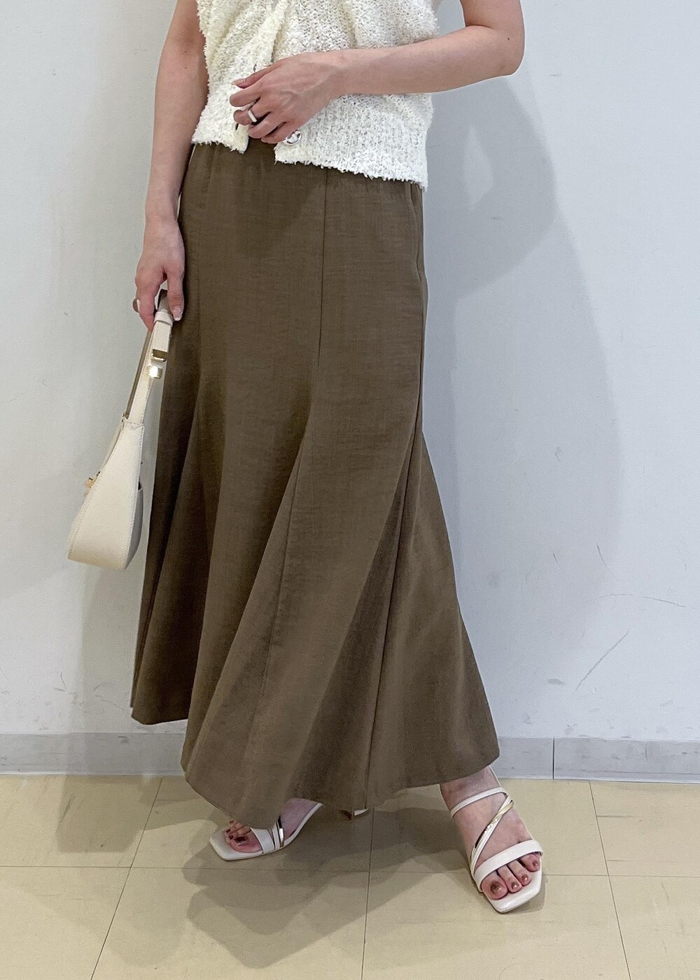 ホワイト系のハンドバッグ、グリーン系のスカート、ホワイト系のサンダルを着用したレディースの春コーディネートの6枚目の写真