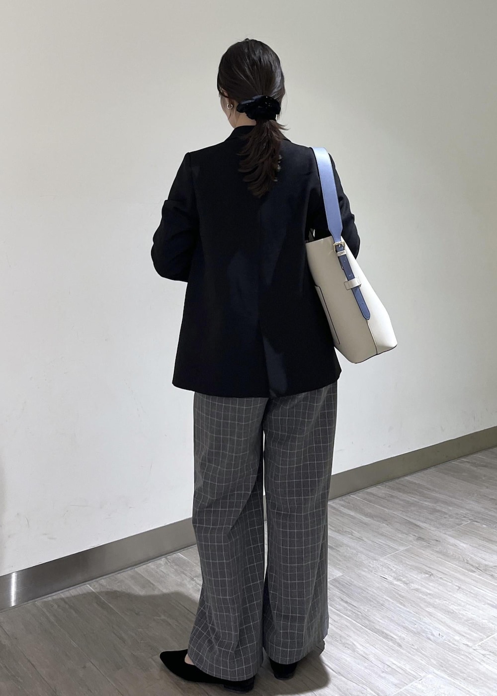 ベージュ系のトートバッグ、ブラック系のテーラードジャケット、ブラック系のチェスターコートを着用したレディースの冬コーディネートの2枚目の写真