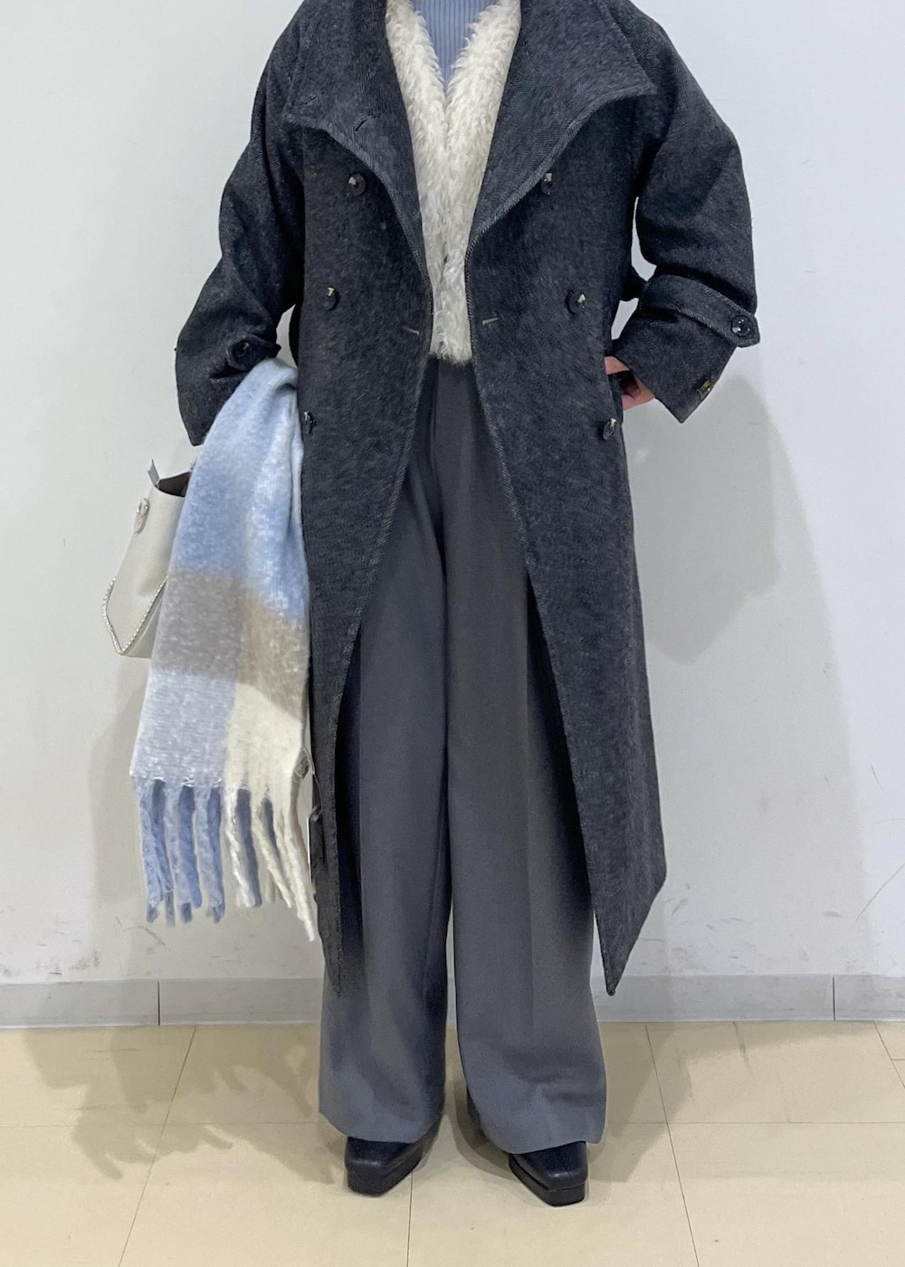 グレー系のスラックス、ホワイト系のベスト、ブルー系のニット/セーターを着用したレディースの秋コーディネートの2枚目の写真