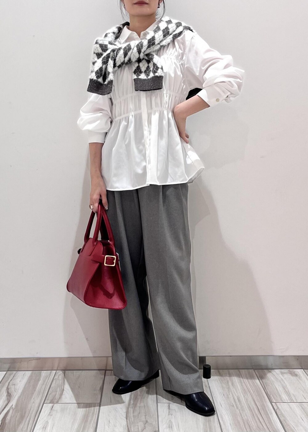 レッド系のトートバッグ、ブラック系のブーツ、ブラック系のカーディガン/ボレロを着用したレディースの秋コーディネートの2枚目の写真