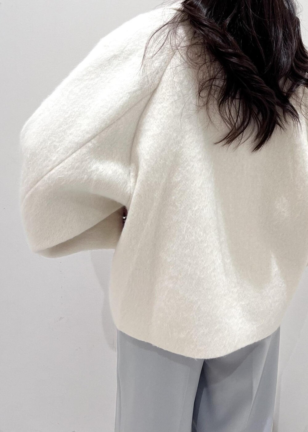 シルバー系のパンプス、シルバー系のショルダーバッグ、ブルー系のスラックスを着用したレディースの秋コーディネートの10枚目の写真