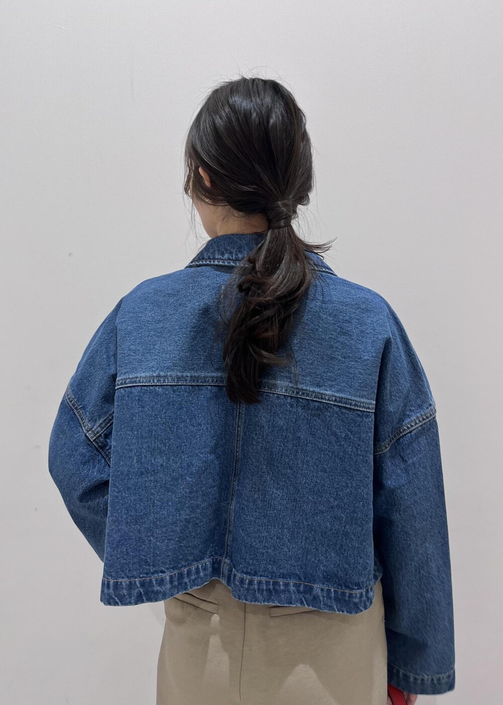 ブルー系のデニムジャケット、ホワイト系のニット/セーター、ベージュ系のスラックスを着用したレディースの冬コーディネートの6枚目の写真