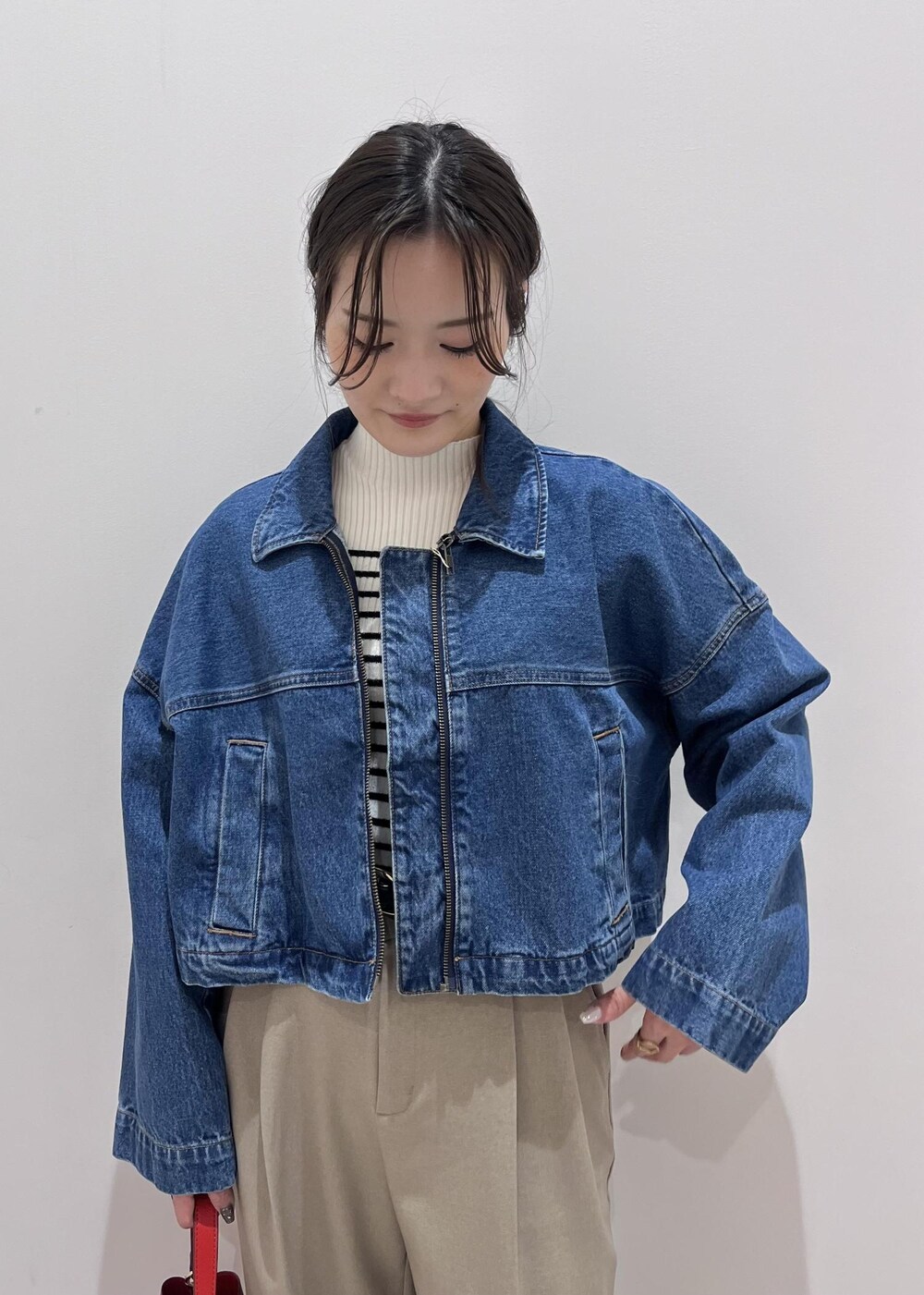 ブルー系のデニムジャケット、ホワイト系のニット/セーター、ベージュ系のスラックスを着用したレディースの冬コーディネートの5枚目の写真