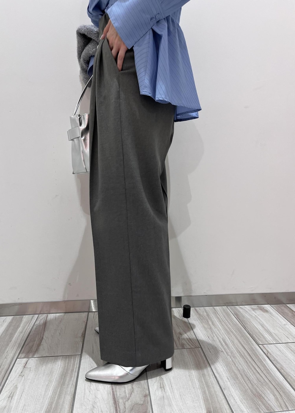 シルバー系のショルダーバッグ、シルバー系のブーツ、グレー系のスラックスを着用したレディースの冬コーディネートの8枚目の写真