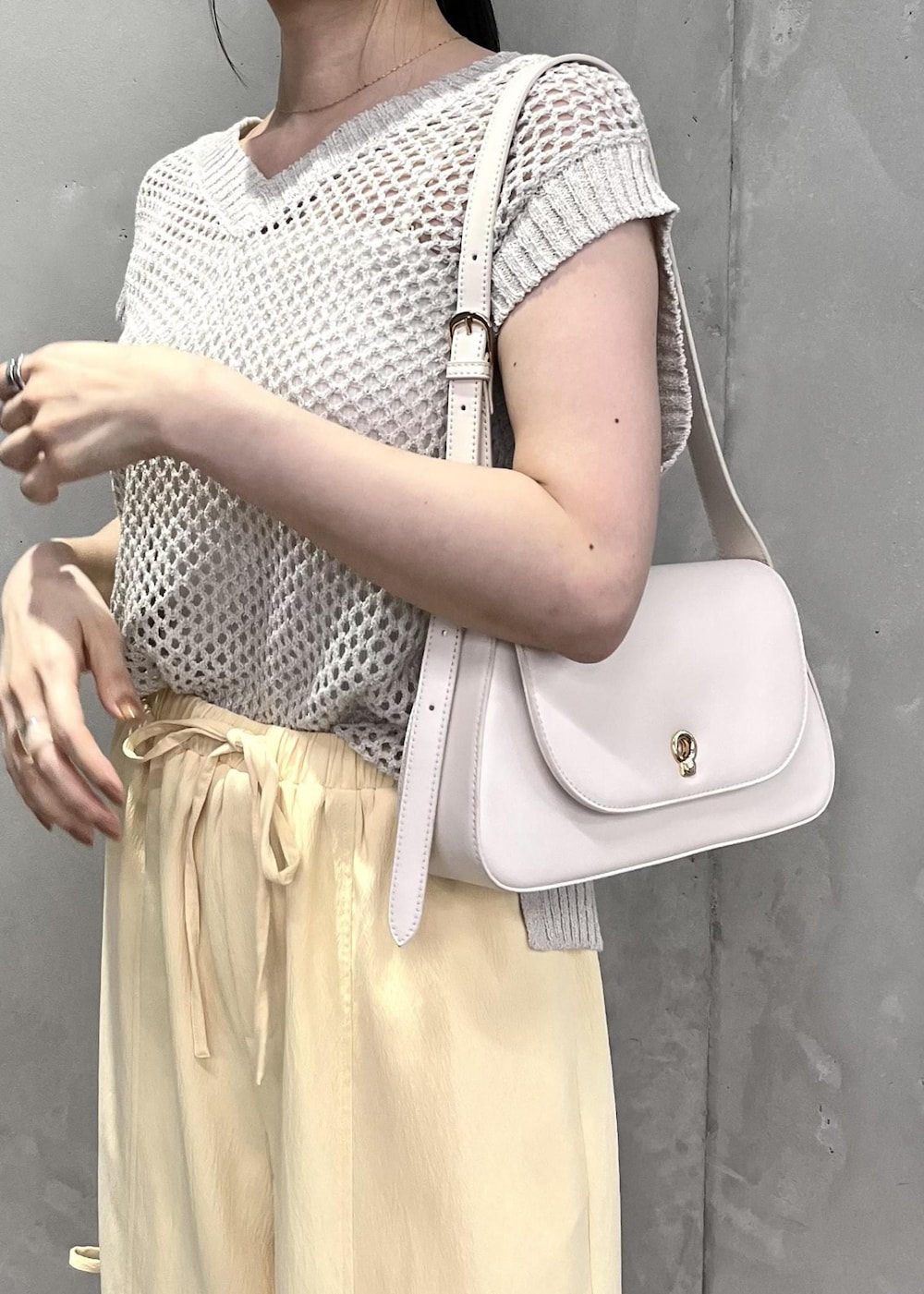 ホワイト系のショルダーバッグ、ホワイト系のサンダル、ホワイト系のベストを着用したレディースの夏コーディネートの2枚目の写真