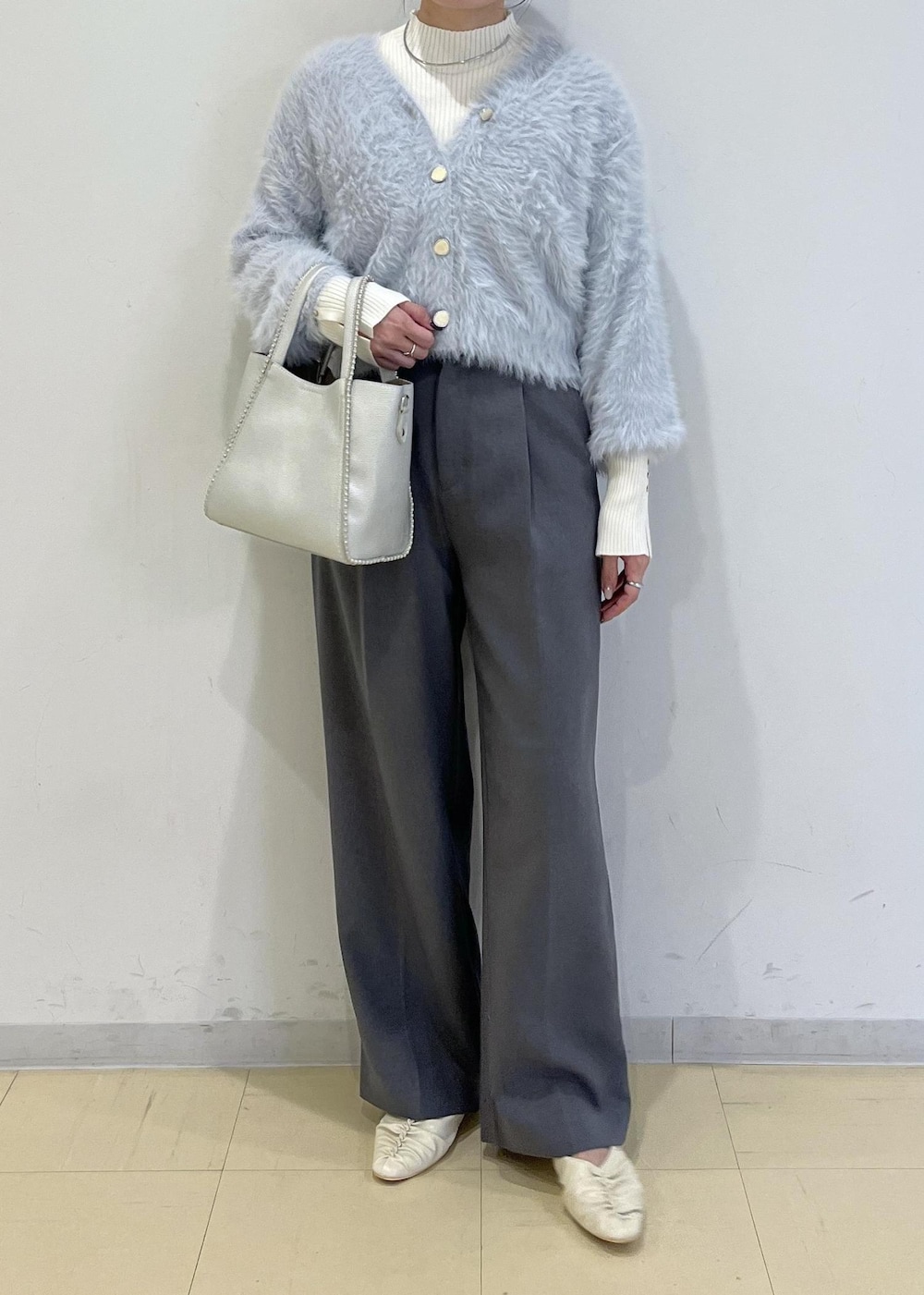 グレー系のスラックス、ホワイト系のパンプス、ブルー系のカーディガン/ボレロを着用したレディースの秋コーディネートの2枚目の写真