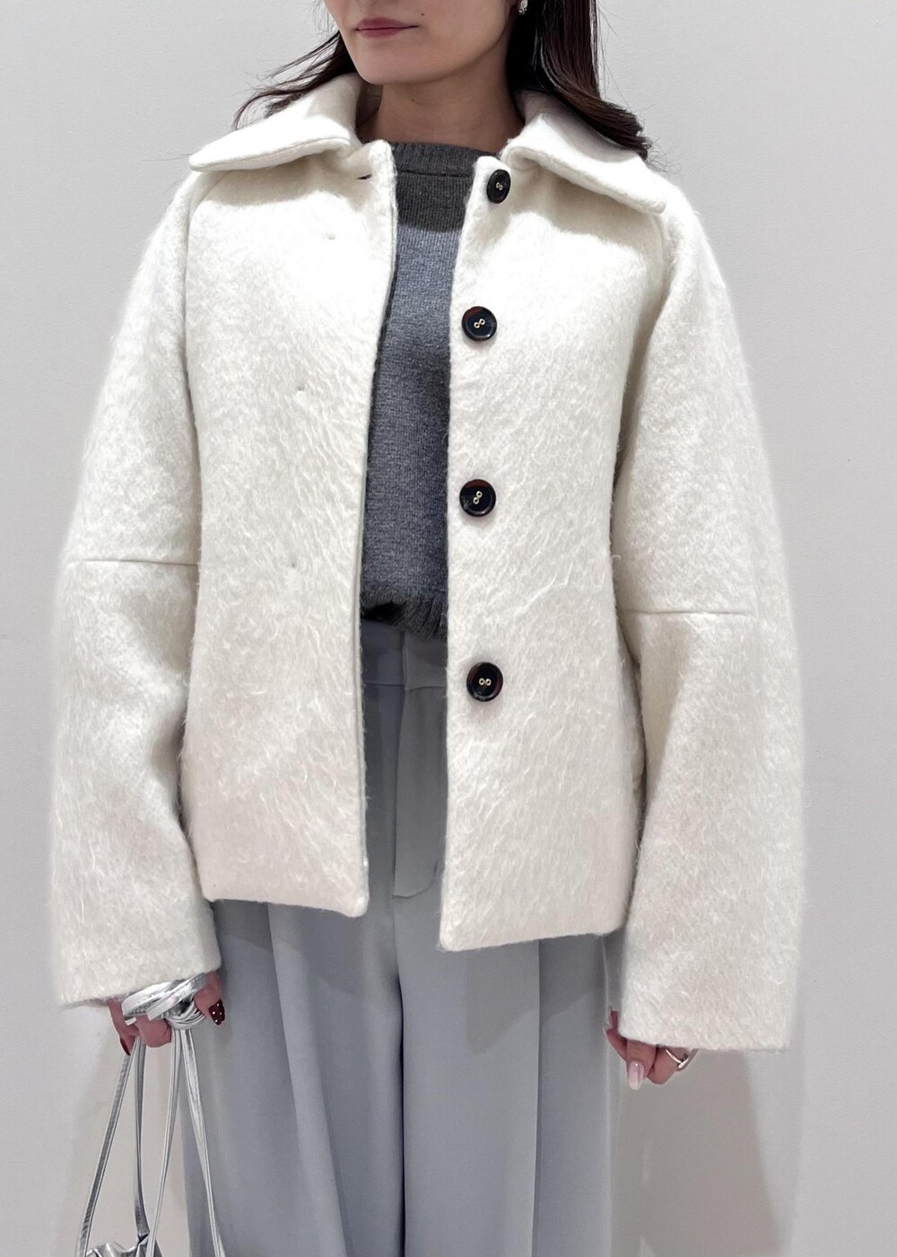 シルバー系のパンプス、シルバー系のショルダーバッグ、ブルー系のスラックスを着用したレディースの秋コーディネートの4枚目の写真