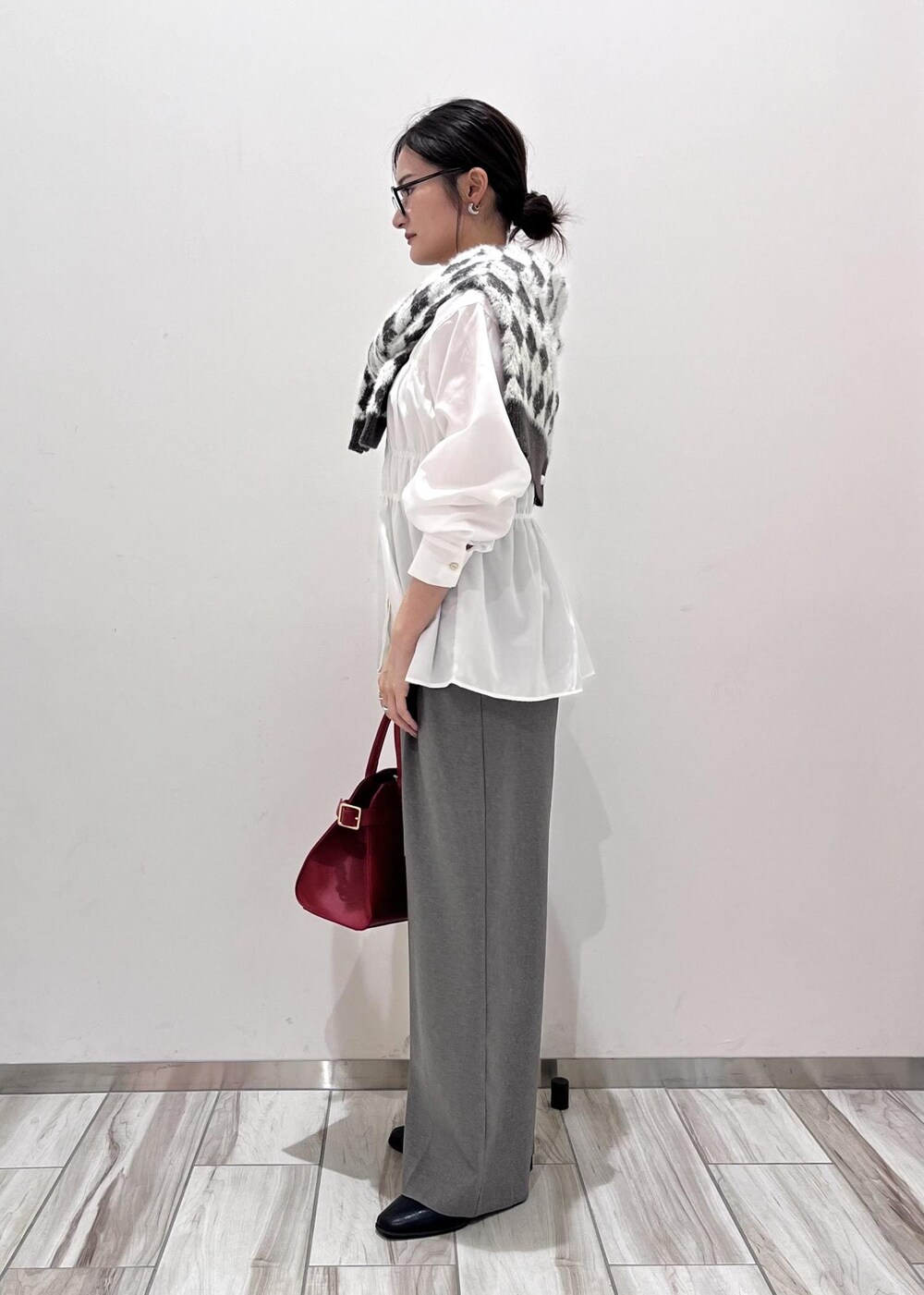 レッド系のトートバッグ、ブラック系のブーツ、ブラック系のカーディガン/ボレロを着用したレディースの秋コーディネートの3枚目の写真