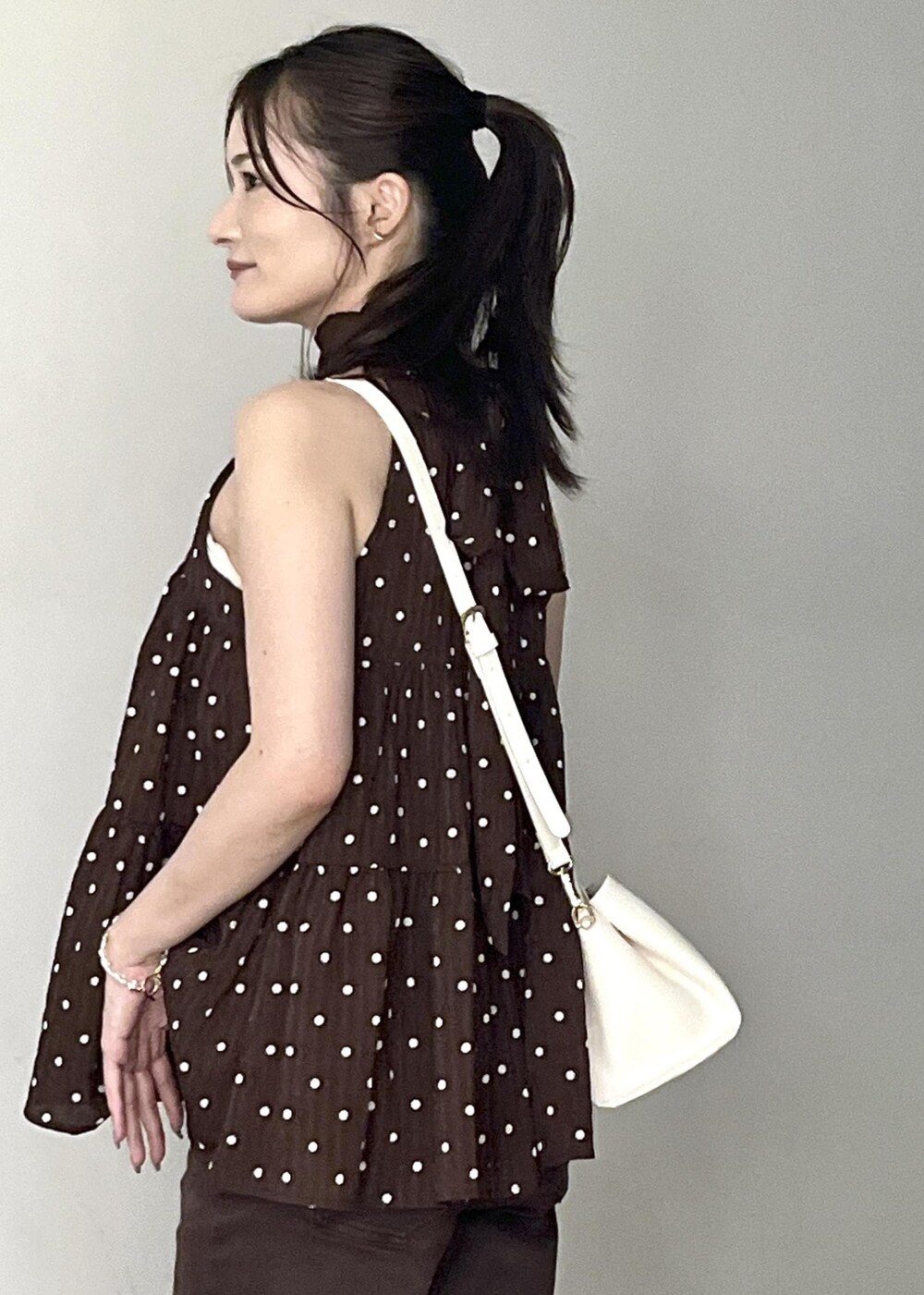 ホワイト系のショルダーバッグ、ホワイト系のサンダル、ブラウン系のデニムパンツを着用したレディースの夏コーディネートの6枚目の写真