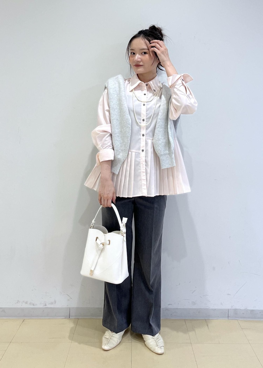 ホワイト系のショルダーバッグ、ホワイト系のパンプス、グレー系のスラックスを着用したレディースの秋コーディネートの2枚目の写真